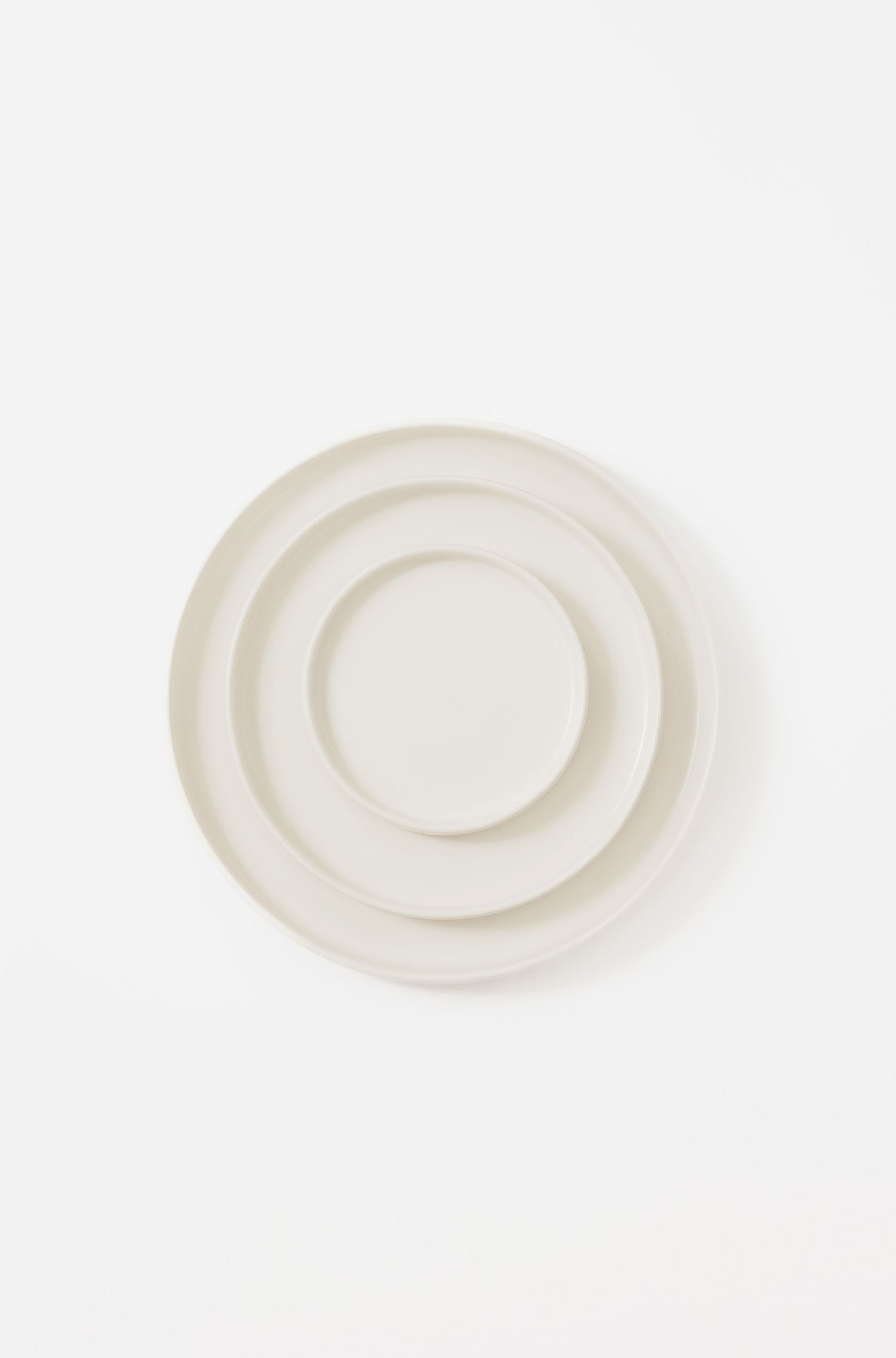 Minimalist white ceramic plate with concentric circle design on light background.