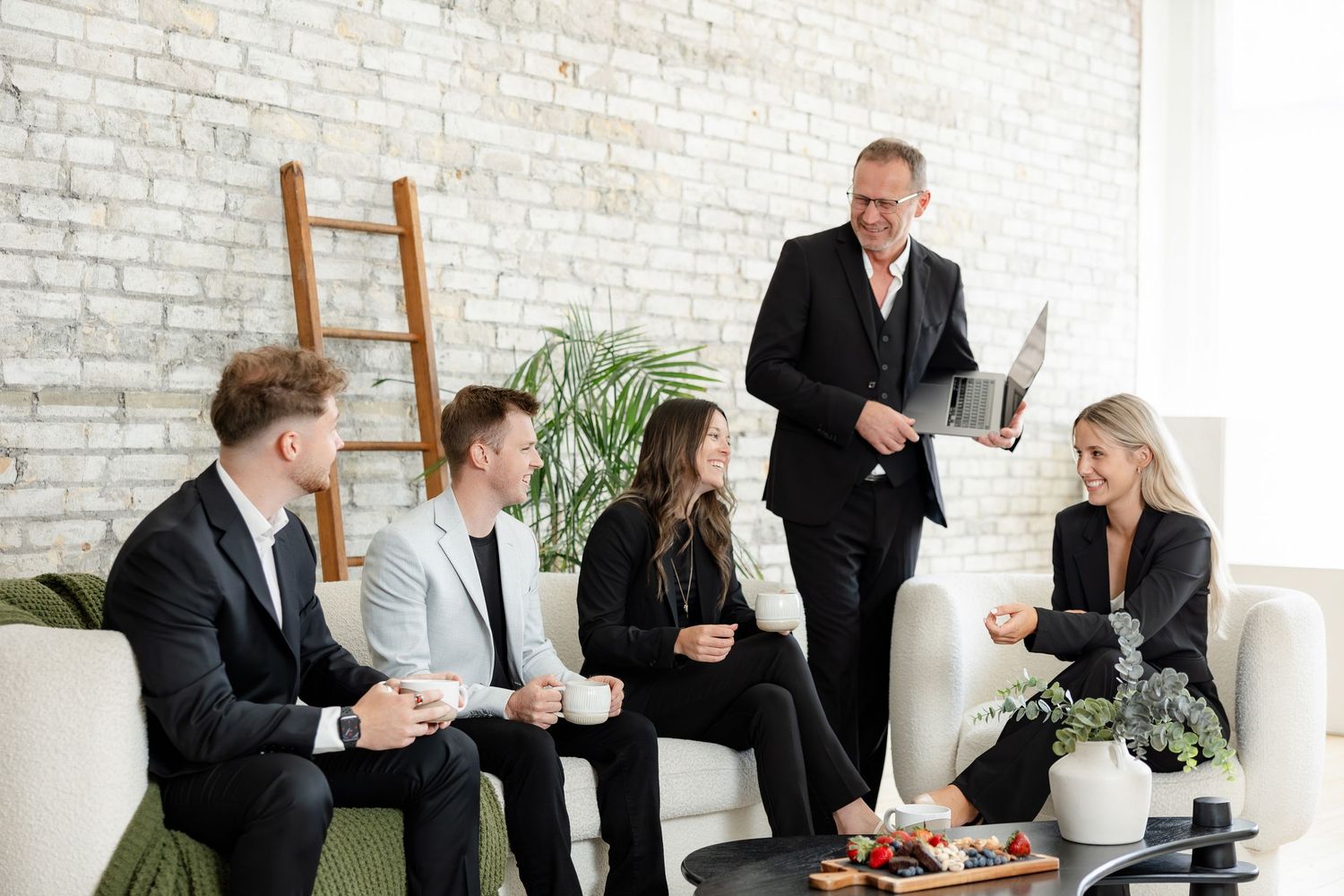 Business team having casual meeting in modern office space with white brick walls.
