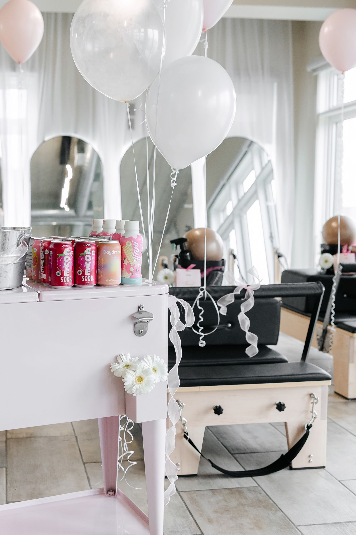 Bright fitness studio decorated with white balloons and pink accents.