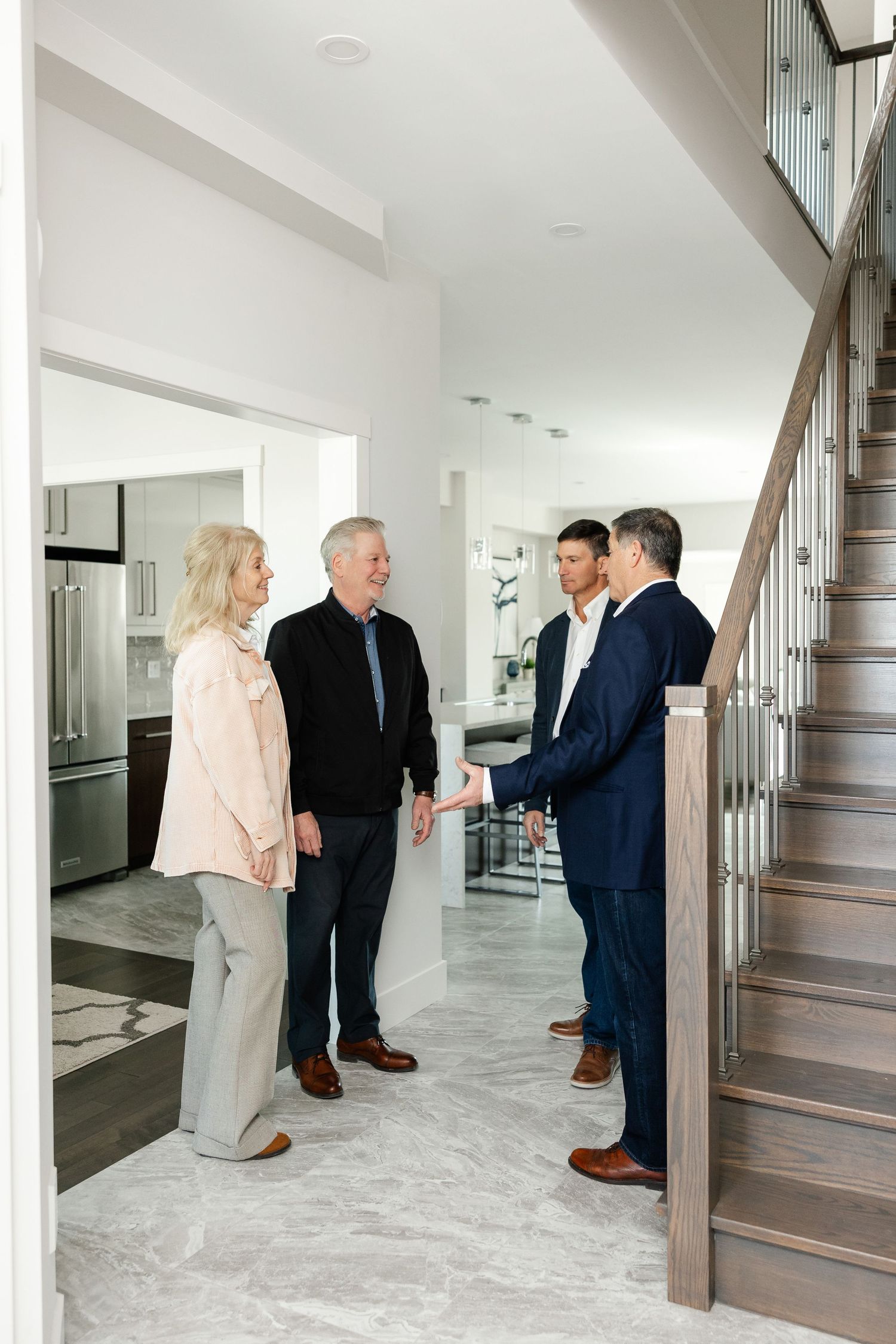 Group touring bright modern home interior with wooden staircase and white walls.