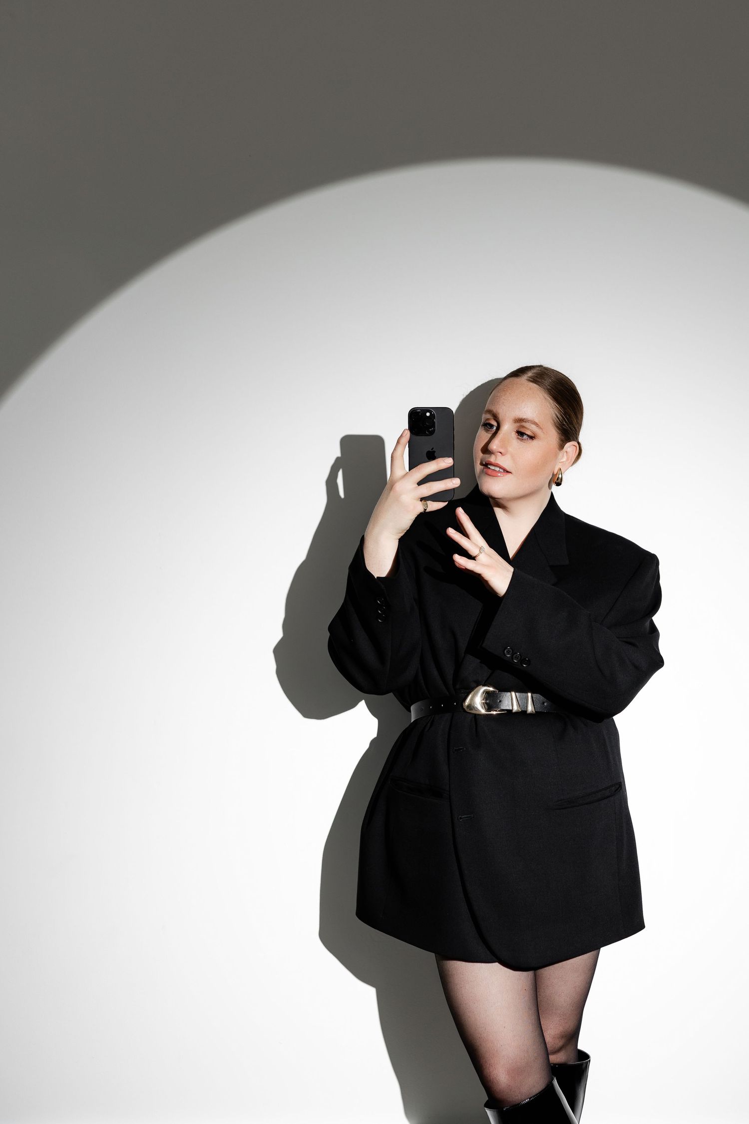 High contrast fashion shoot featuring model in black against stark white background.