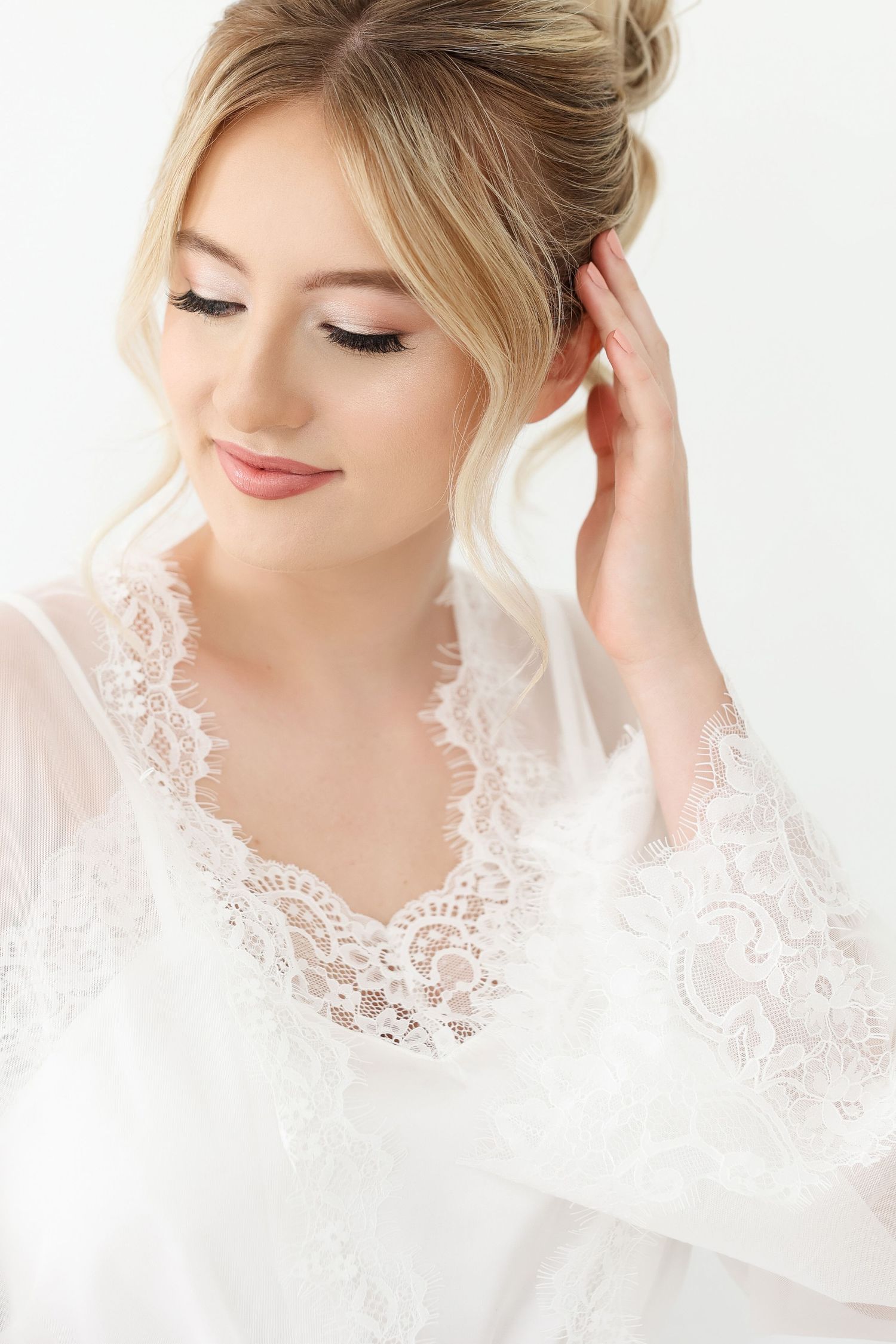 Delicate white lace veil and bridal robe details shown in soft natural lighting against white background.