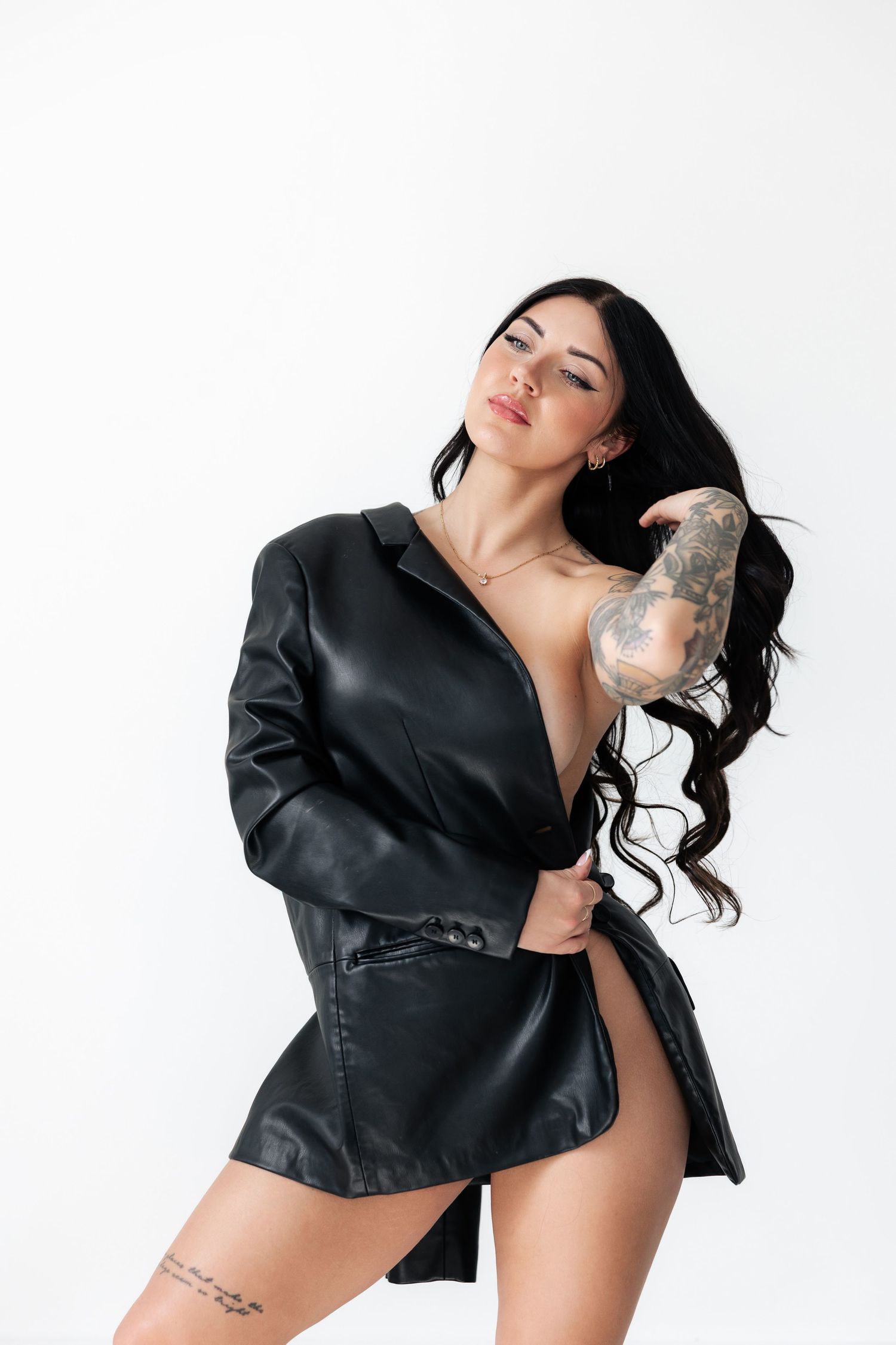 Model wearing black leather jacket poses dramatically in studio setting.