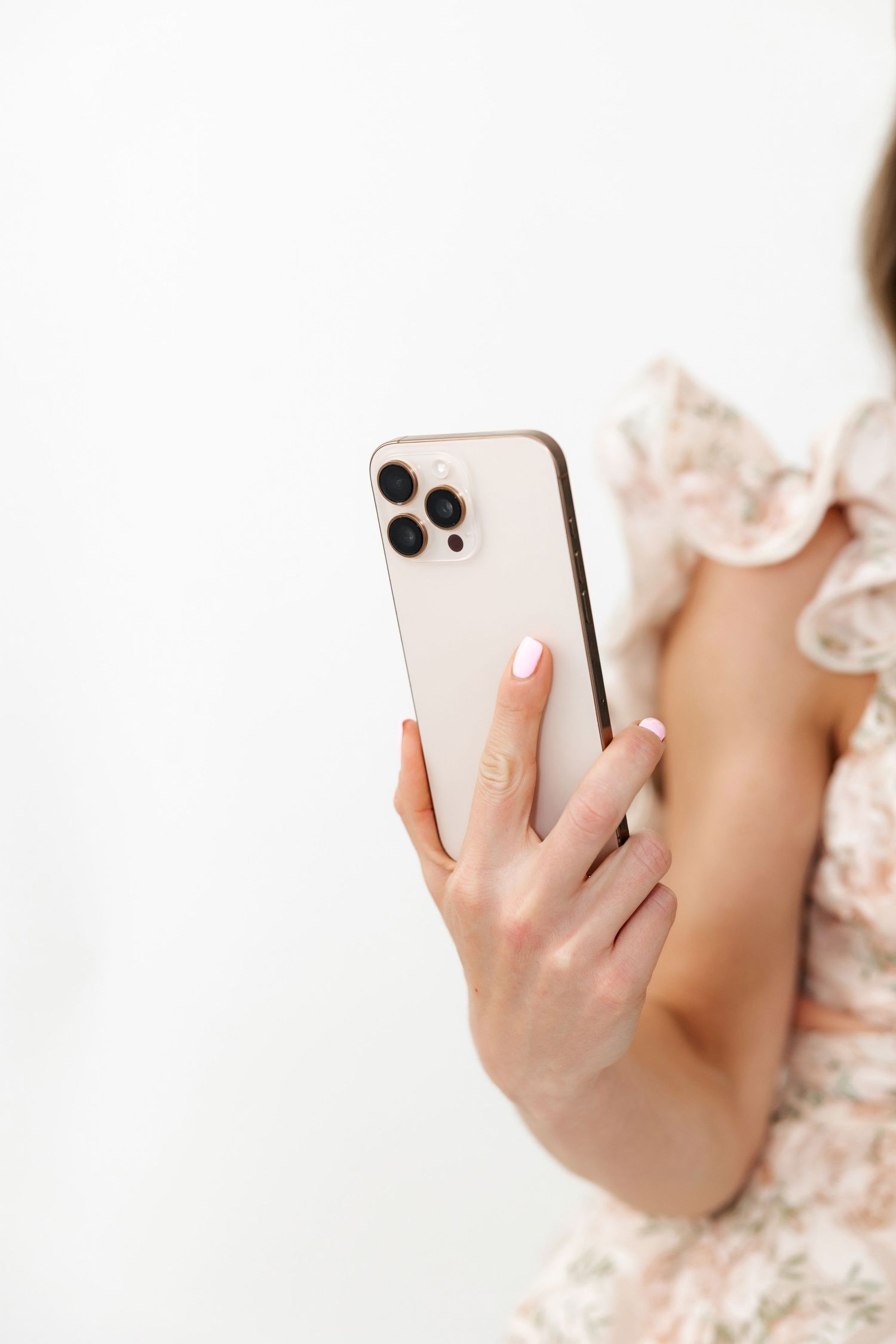 Close-up shot of hands holding rose gold iPhone against floral fabric.