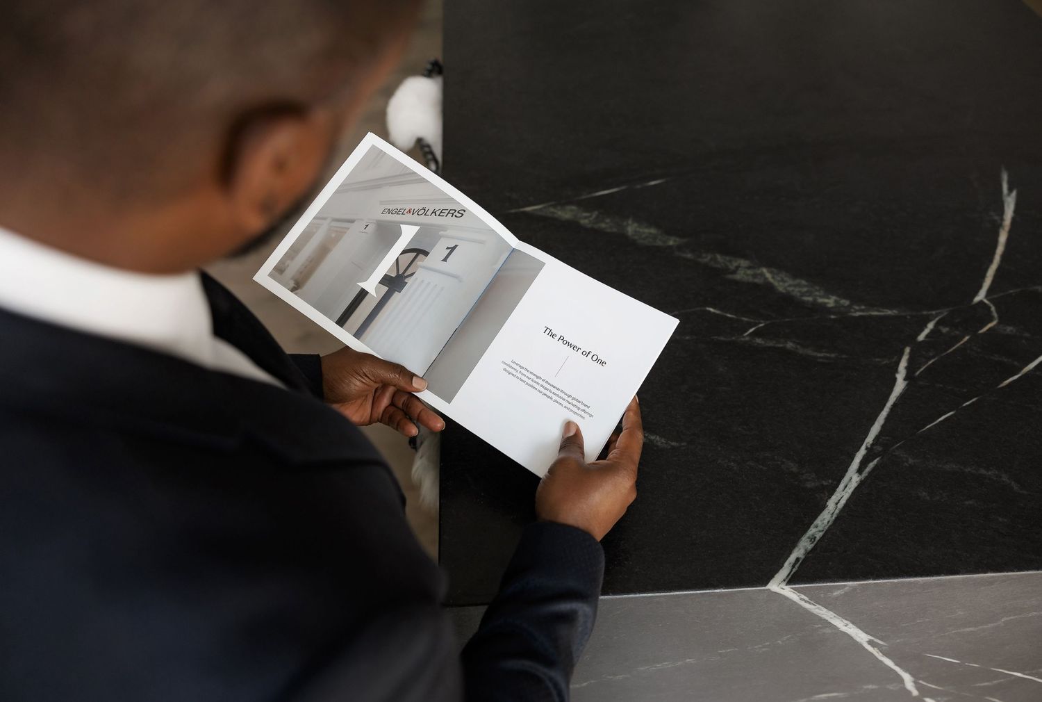 Person holding business cards over dark marble countertop surface.