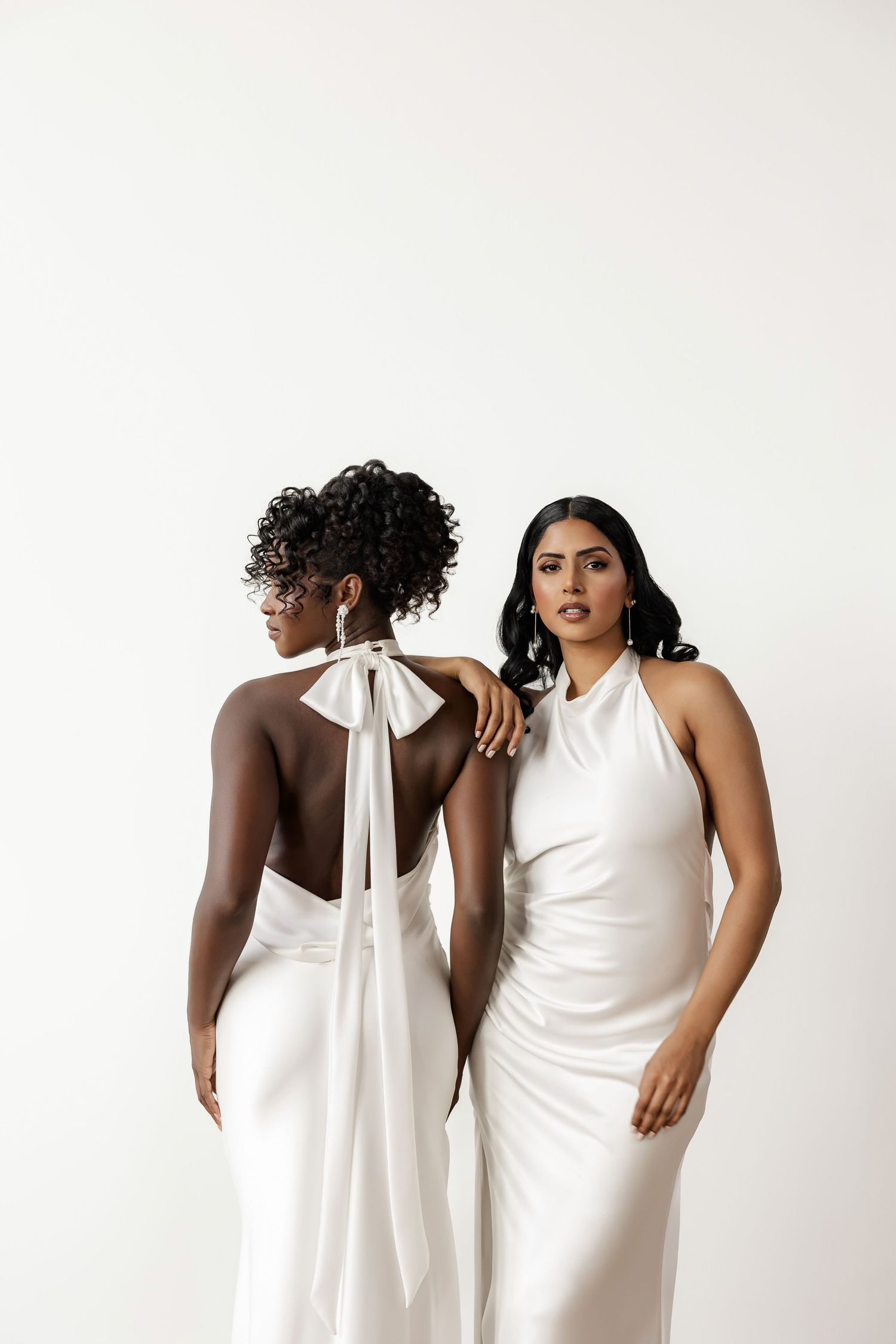 Models in white wedding gowns showing back details and bow accents.