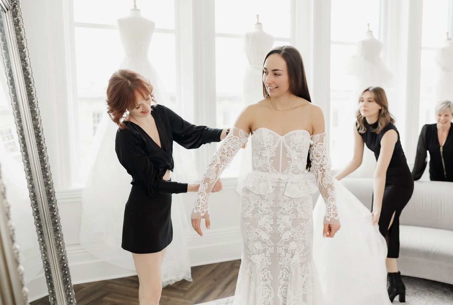Wedding dress consultation in a bright white studio with assistants helping with the gown.