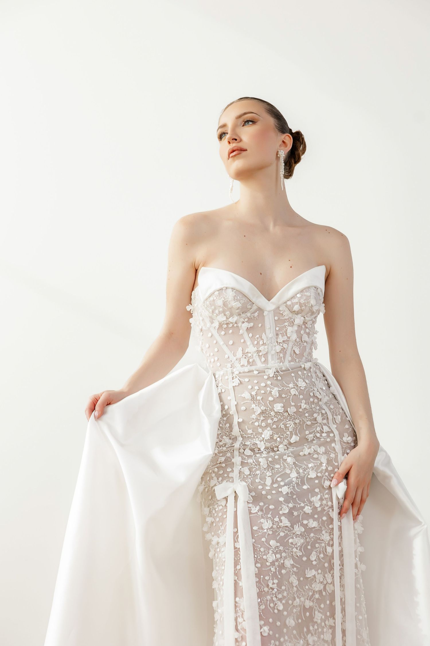 Strapless bridal gown with sheer overlay and floral embellishments shown from multiple angles.