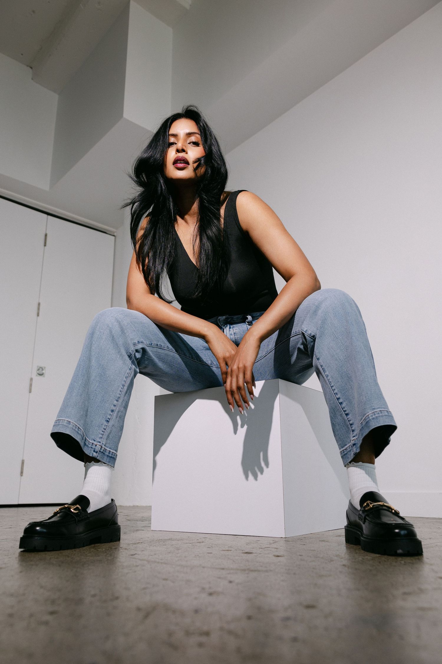 Low-angle fashion photography sequence featuring wide-leg jeans and boots on concrete floor.