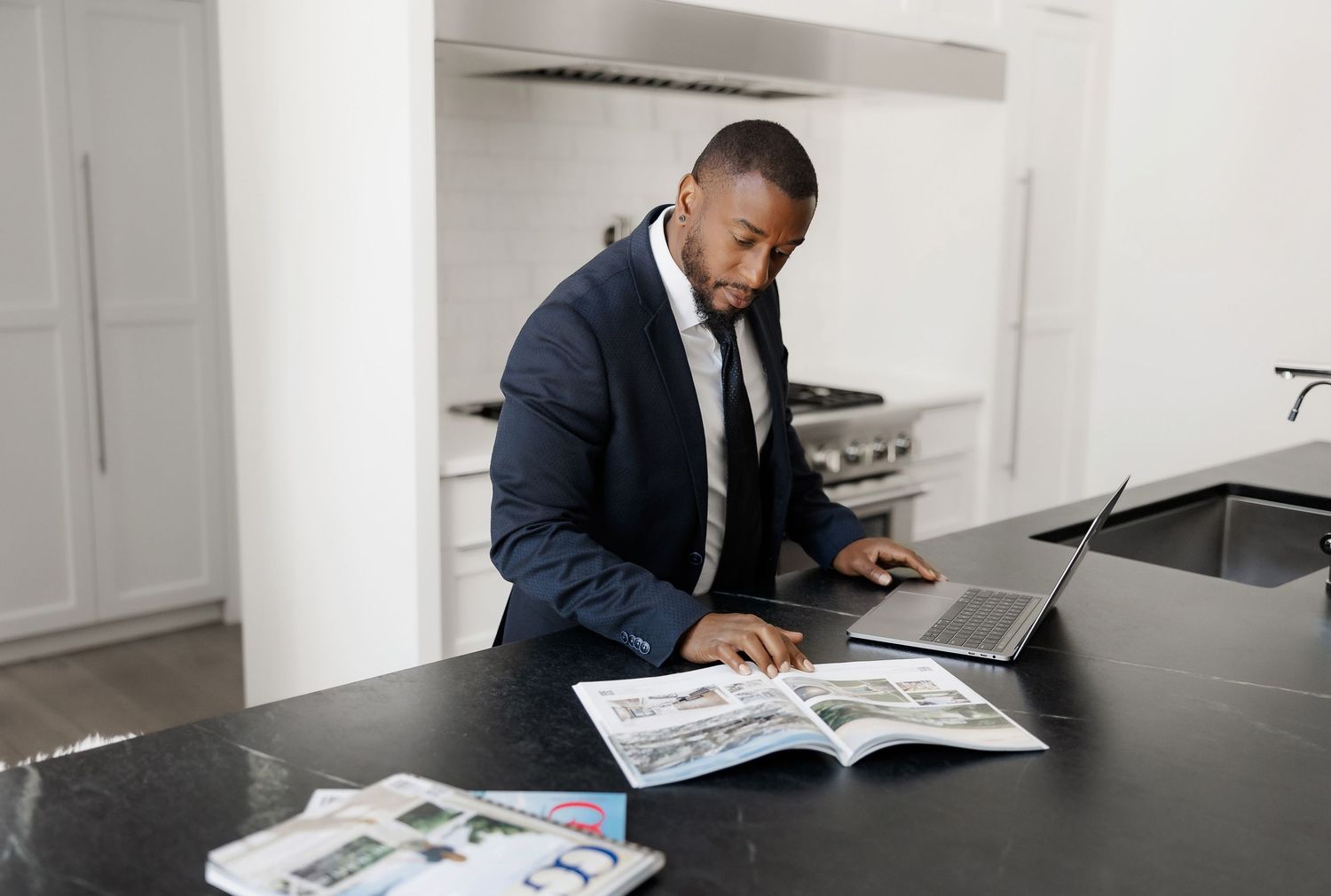 Professional reviewing documents at black marble kitchen island.