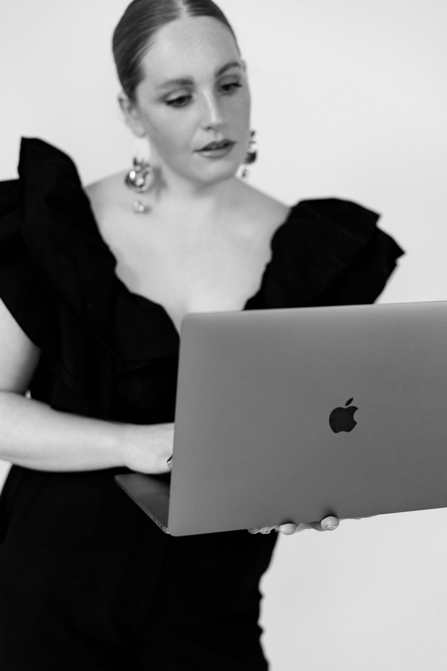 Black and white portrait showing MacBook user in elegant black dress.