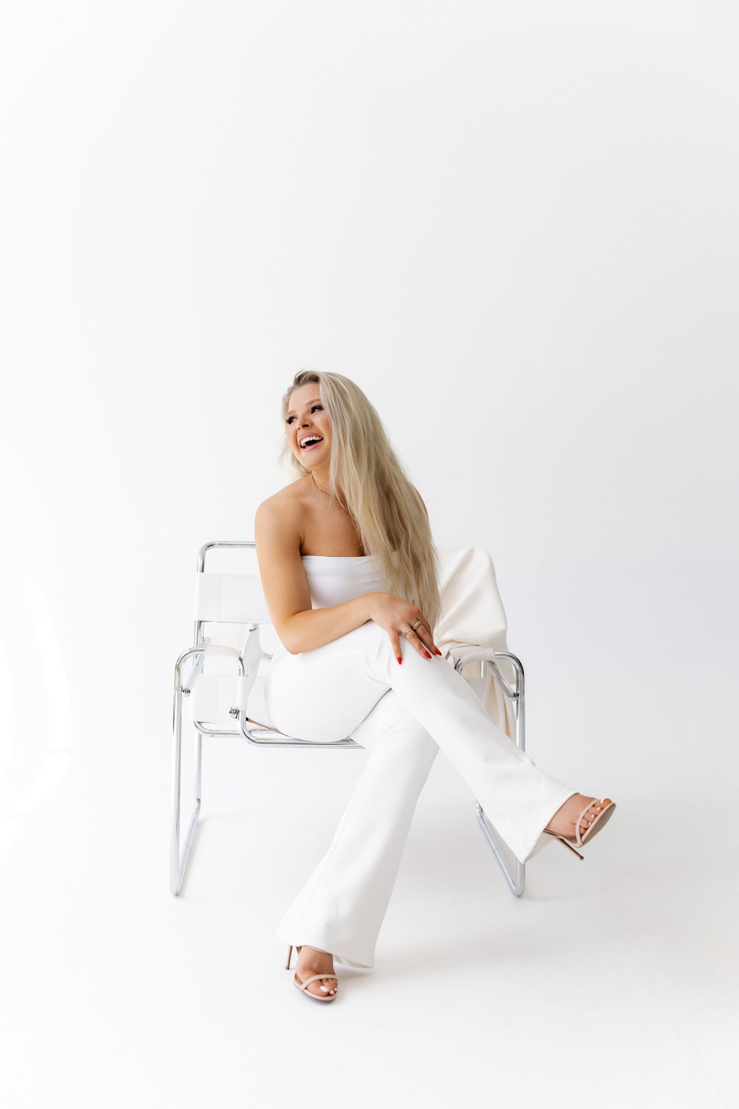 Model in white outfit creates dynamic poses on clear furniture against white background.