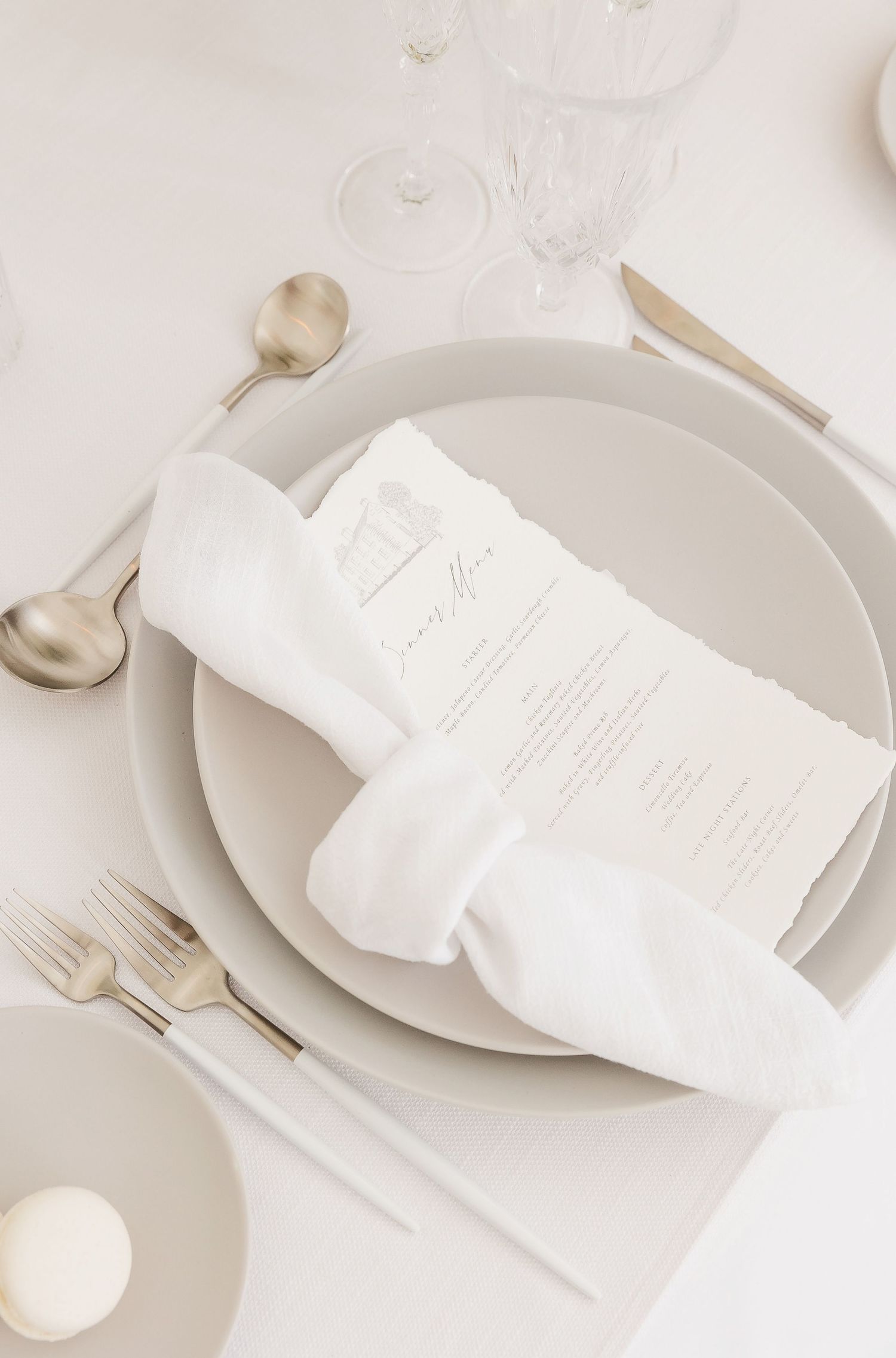 Clean white table setting featuring menu cards and elegant silverware on pale gray plates.