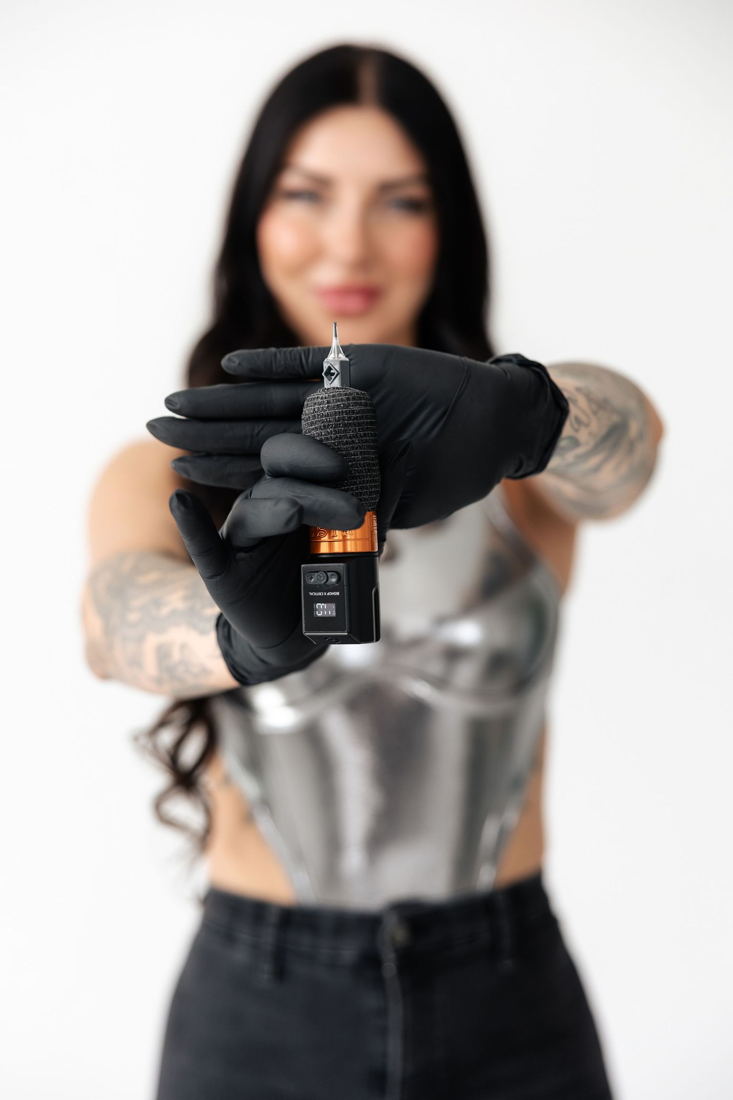 Hands in black gloves holding small electronic device against white background.