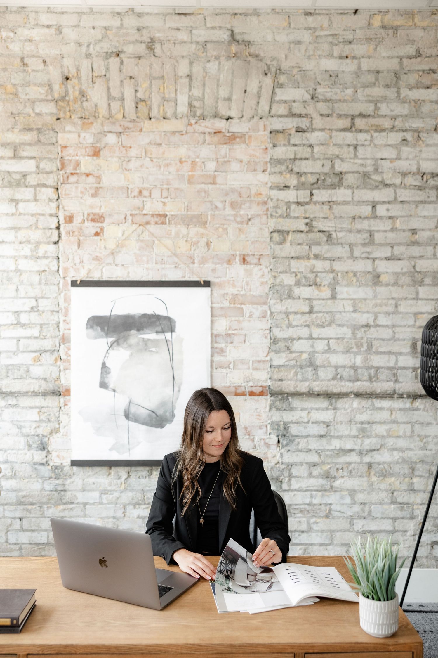 Modern office workspace with laptops and white brick wall background.