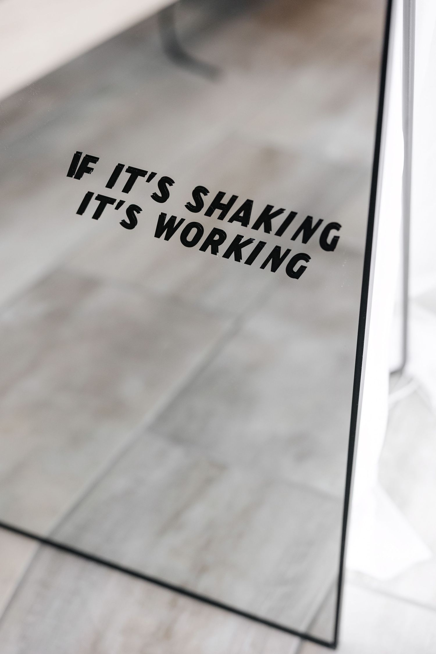 Close-up of motivational text on reflective surface in modern fitness space.