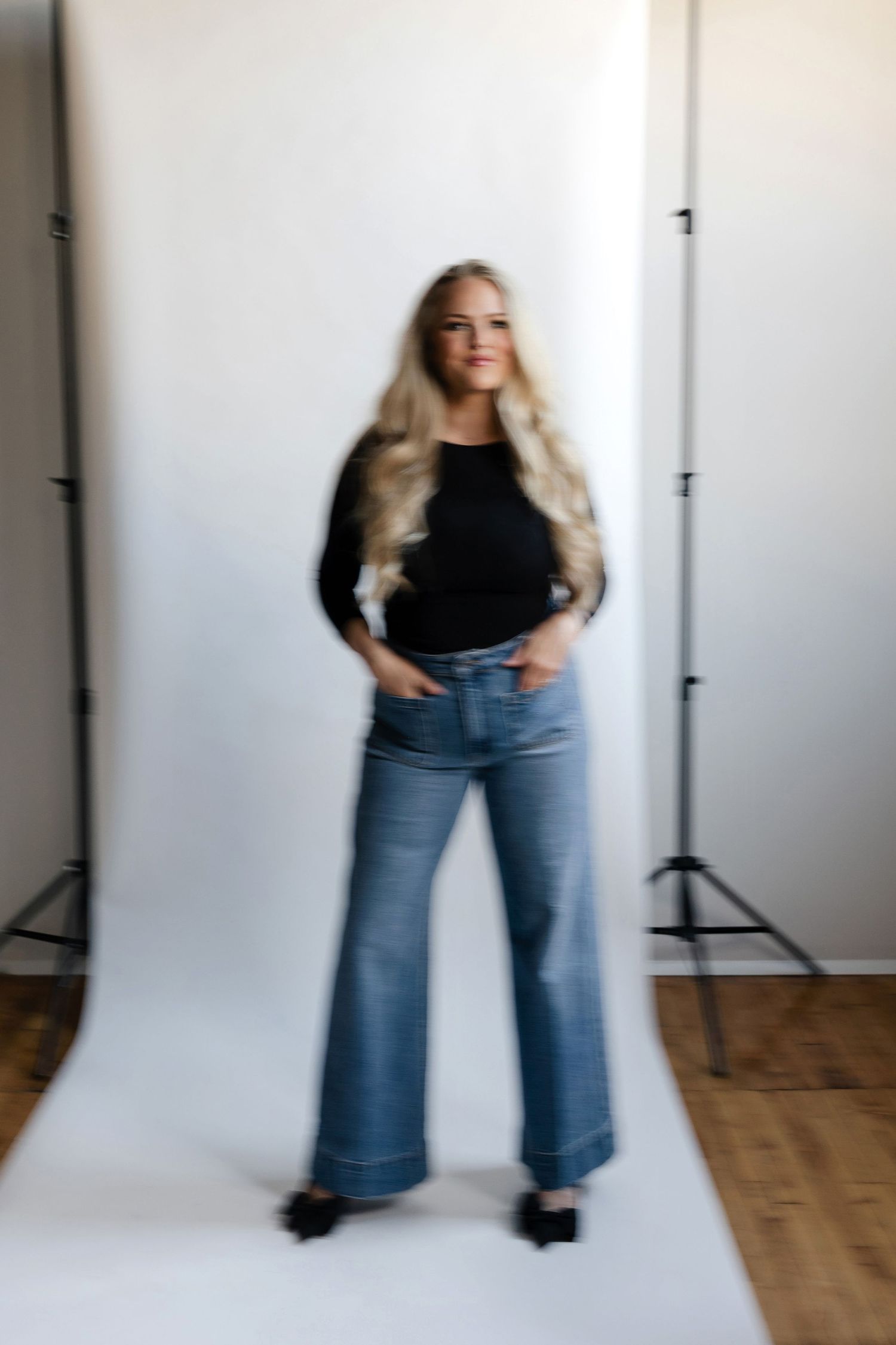 Woman in casual wear dancing against white studio background.