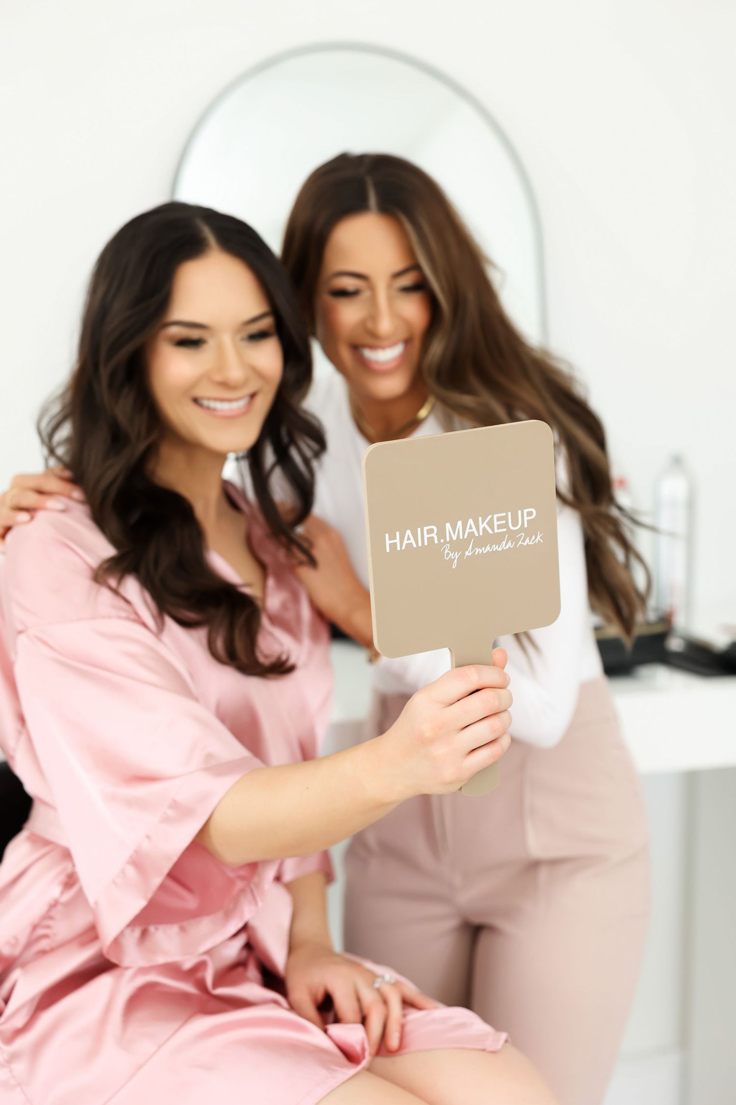 Two people reviewing a hair and makeup portfolio in a bright studio.