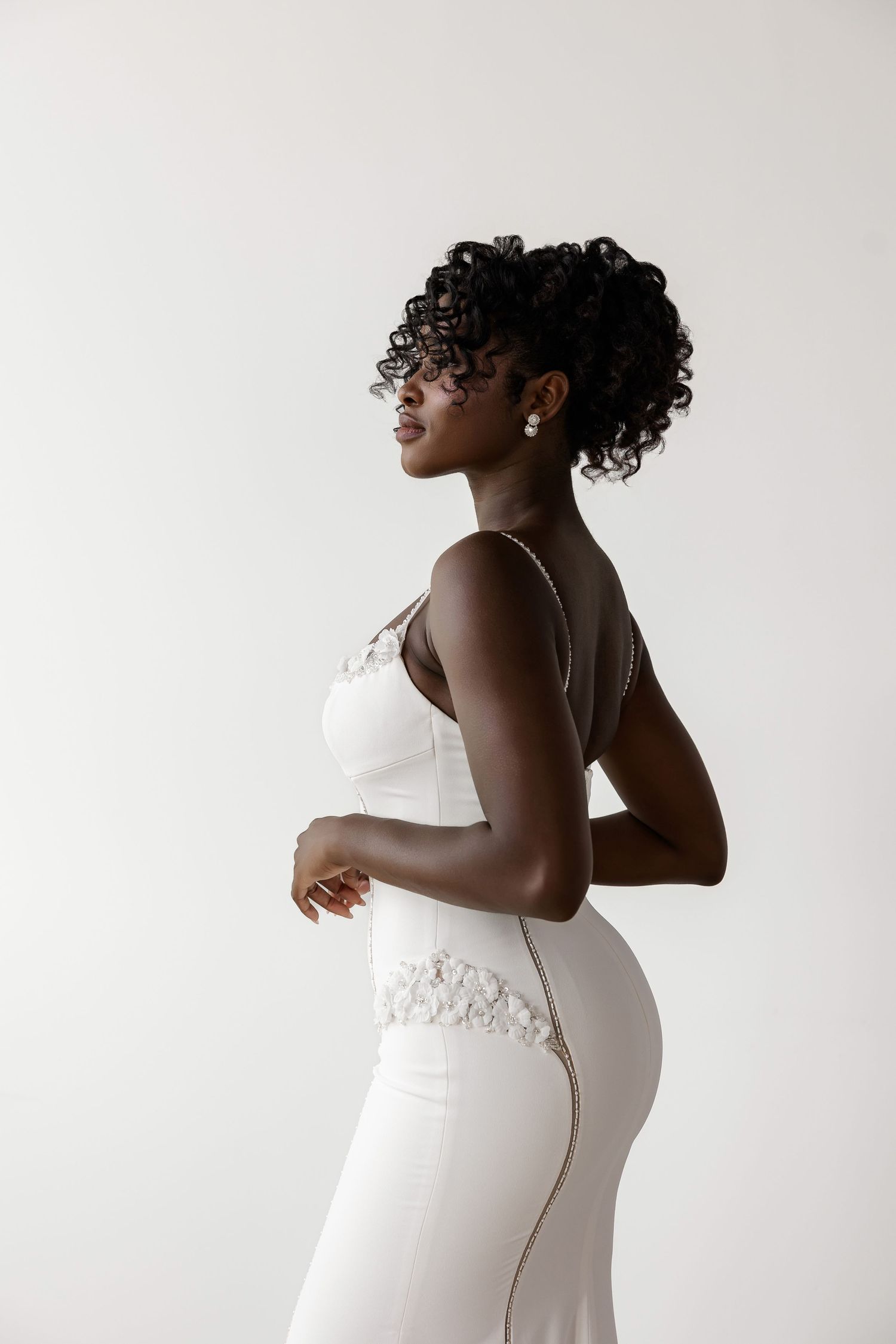 Fitted white wedding dress with lace trim detail shown in side profile.