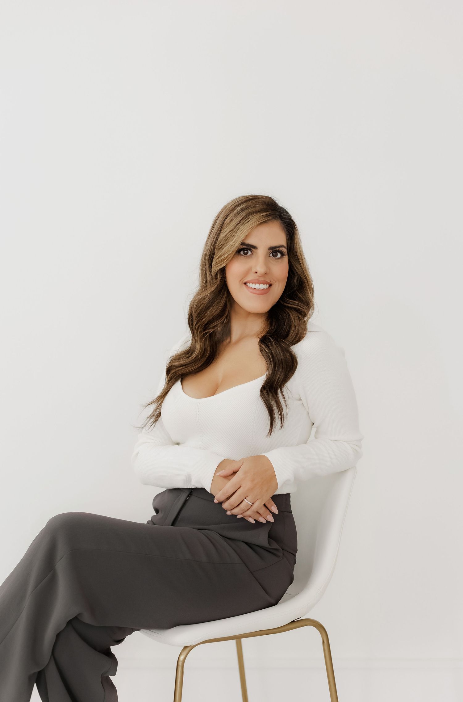 Modern lifestyle photo of someone relaxing in a white chair wearing grey pants and white top.