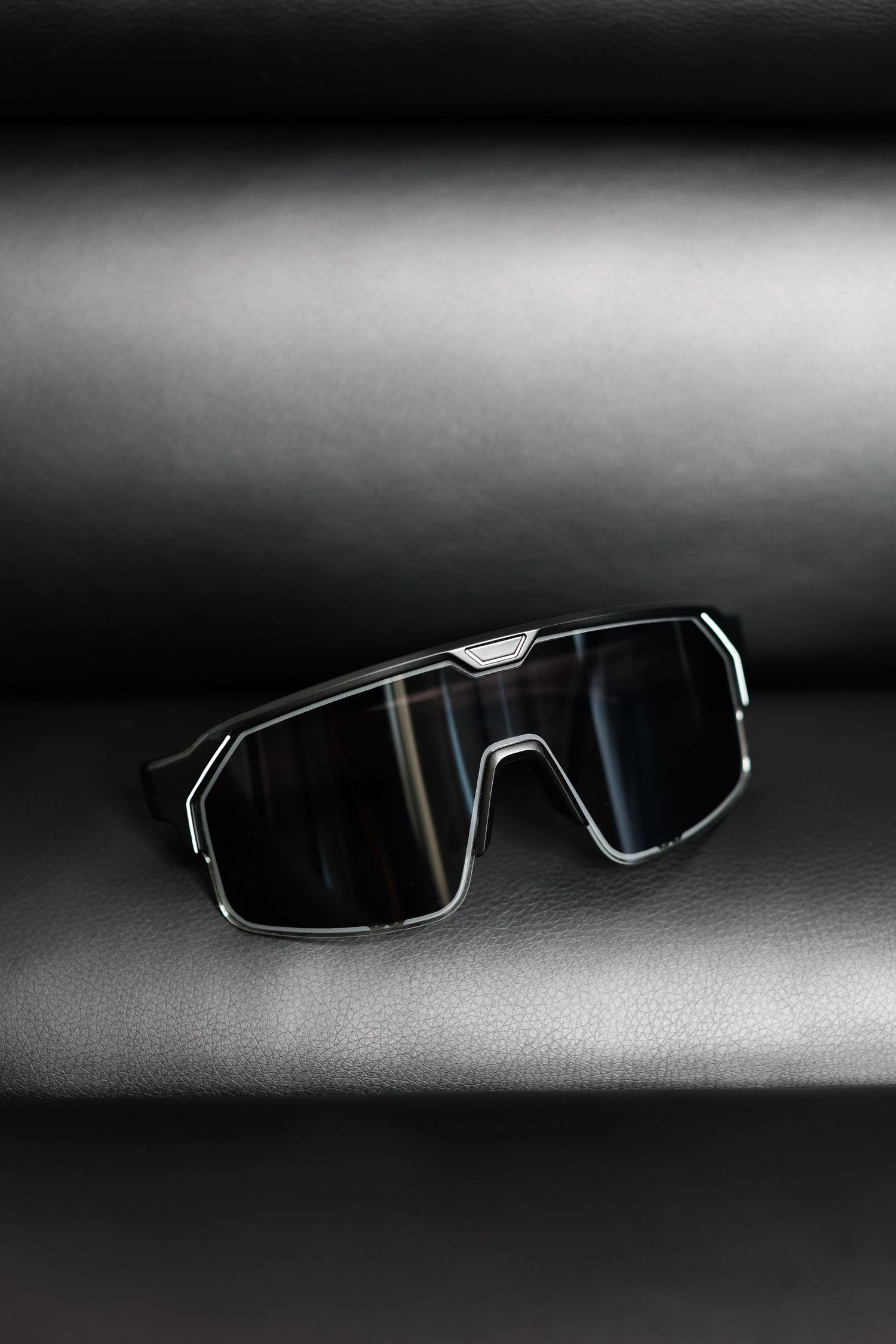 Artistic still life of modern black sunglasses against dark gradient background.