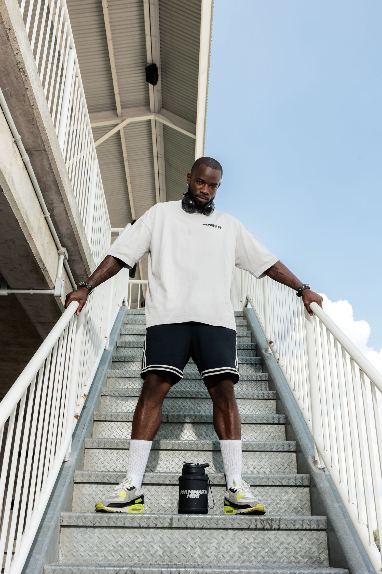 Person in white shirt and shorts walking down metal stairs in sequence of action shots.