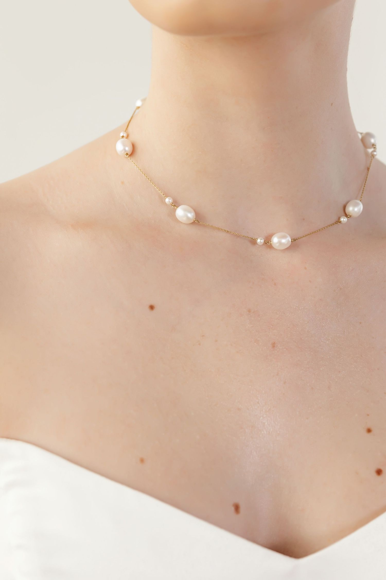Delicate pearl wedding necklace on model wearing white bridal gown.