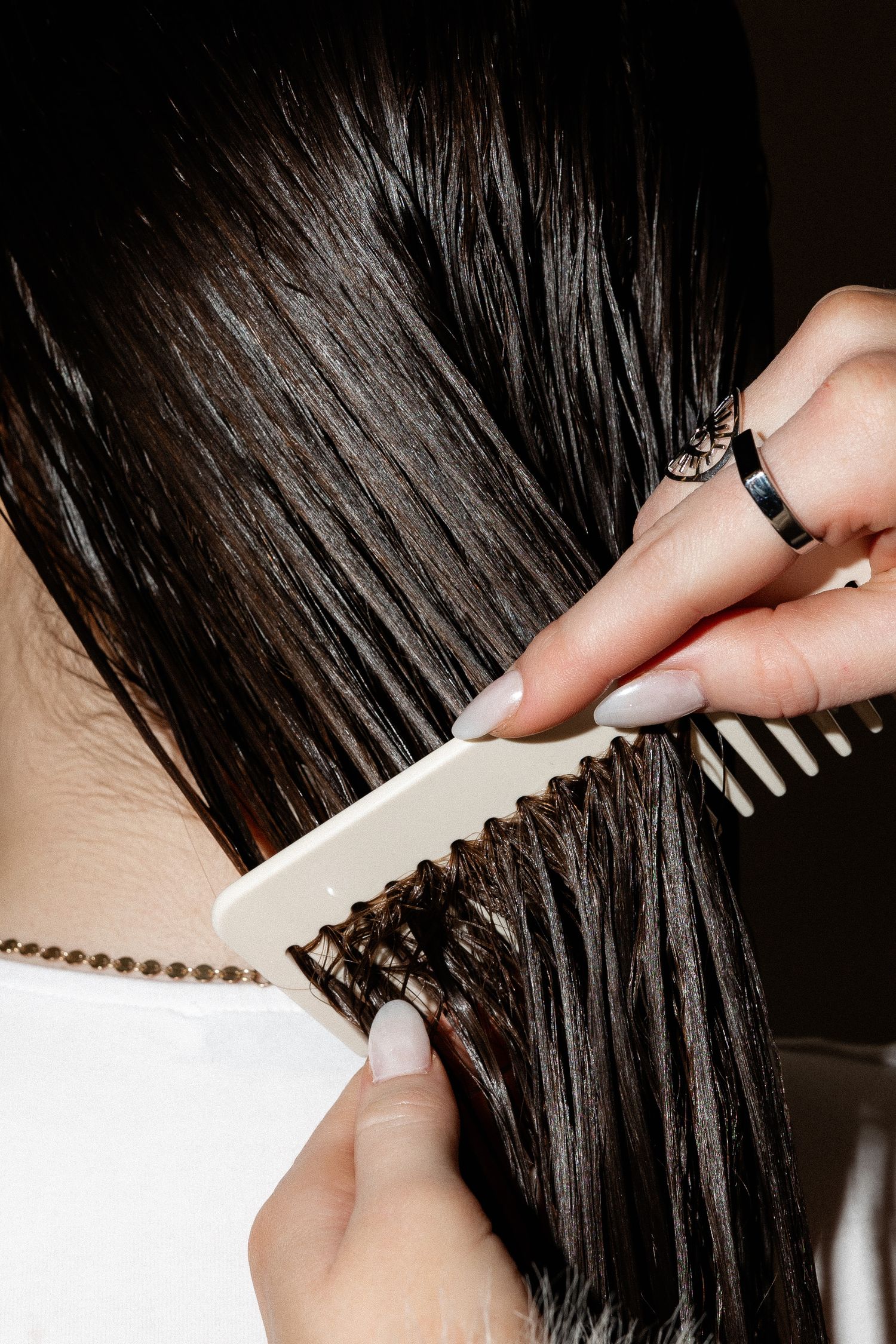 Detailed view of combing through wet dark hair sections.