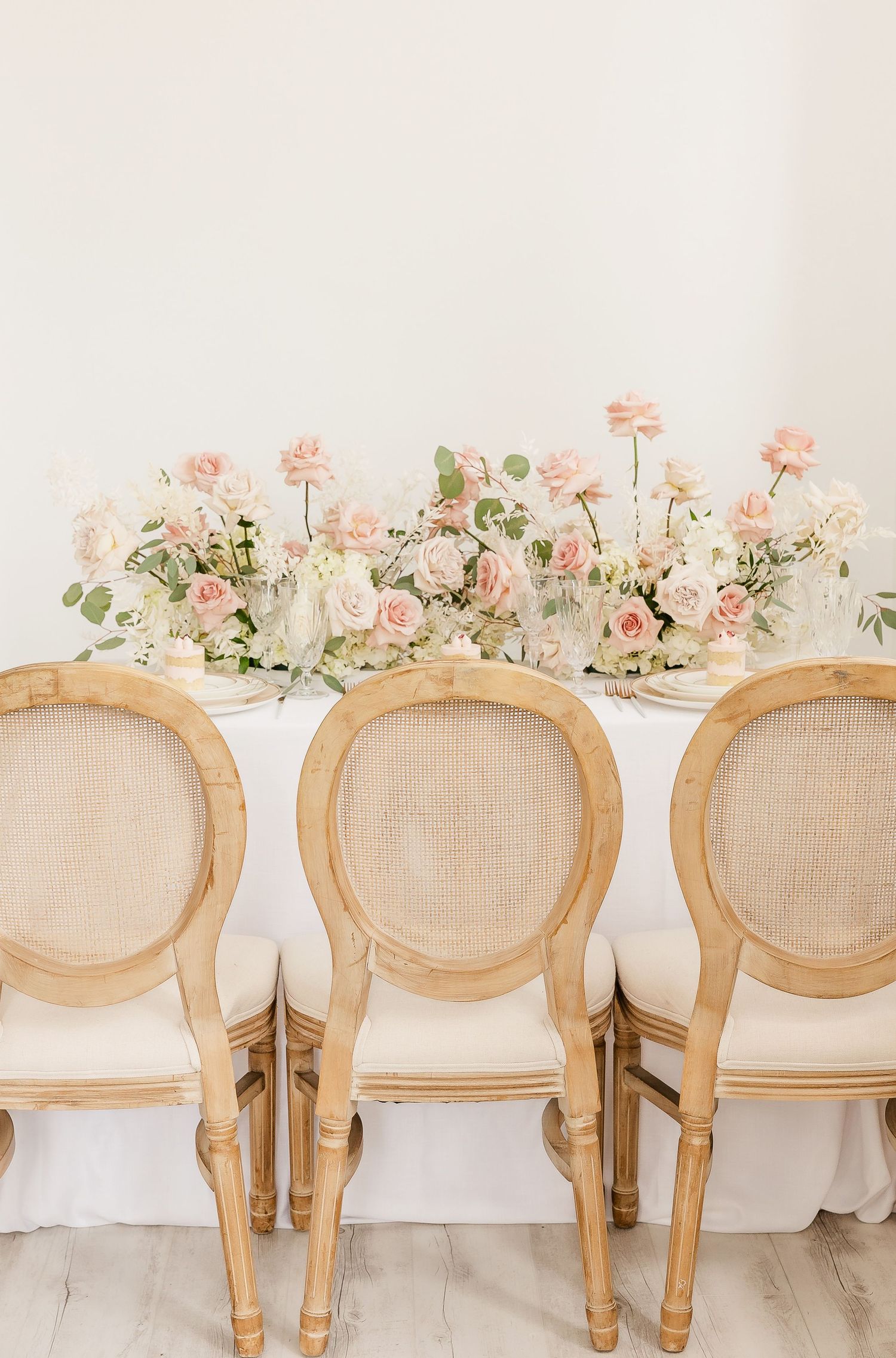 Row of elegant French provincial chairs with cream upholstery and floral table decor.