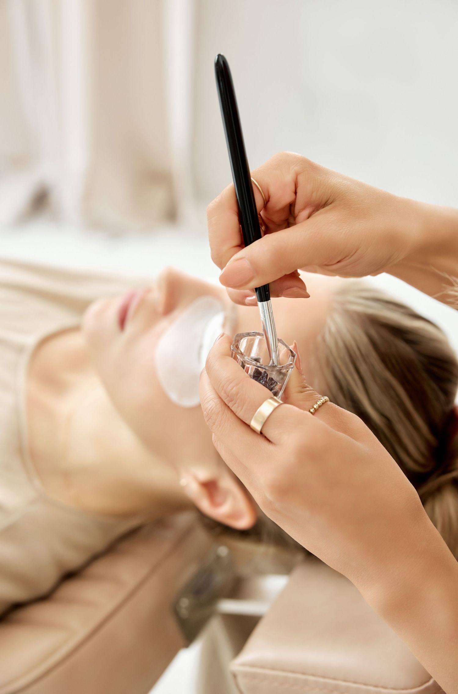 Side view of eyelash extension application process with professional tools.