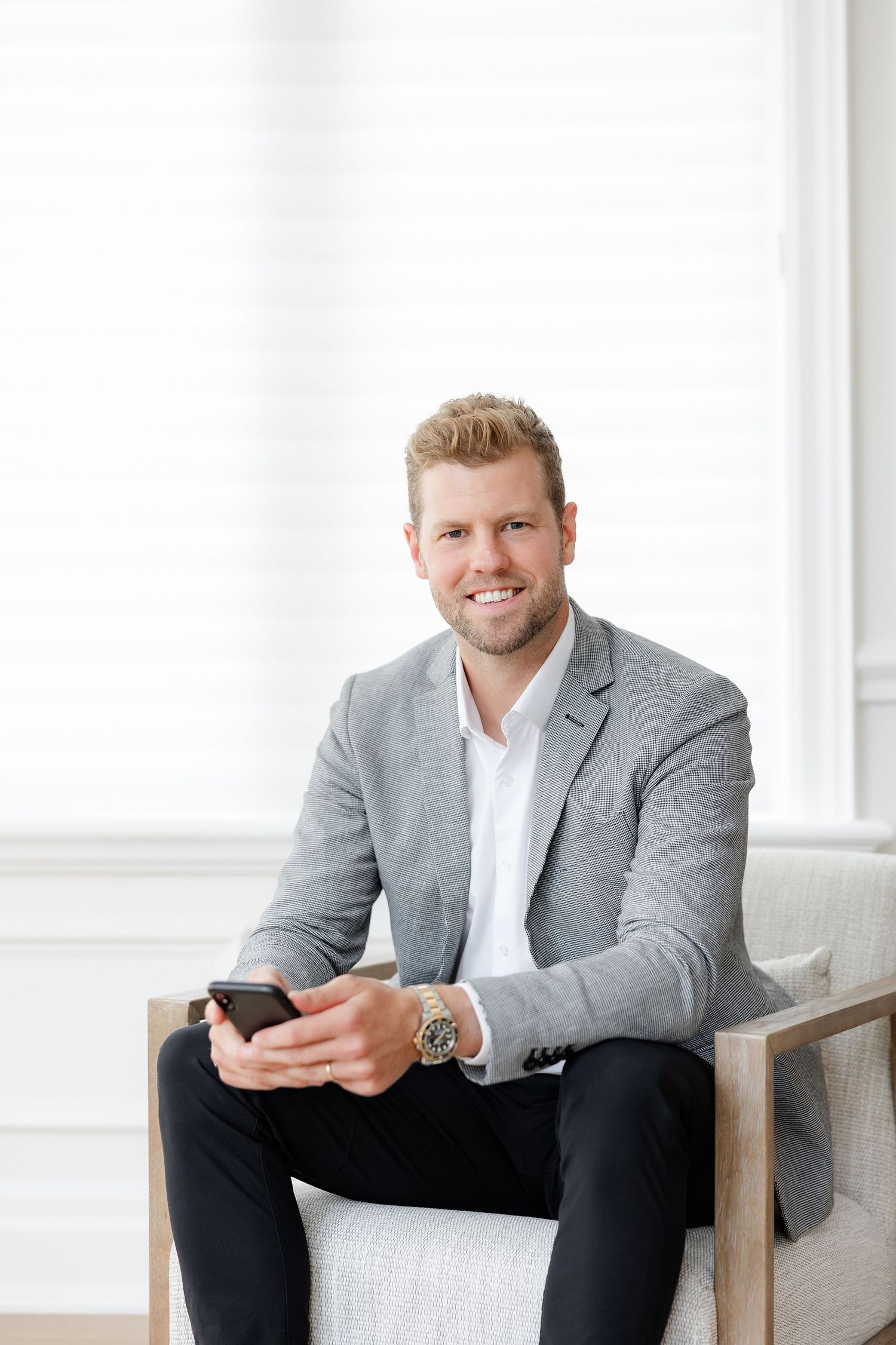 Professional in grey suit sitting in bright office setting.