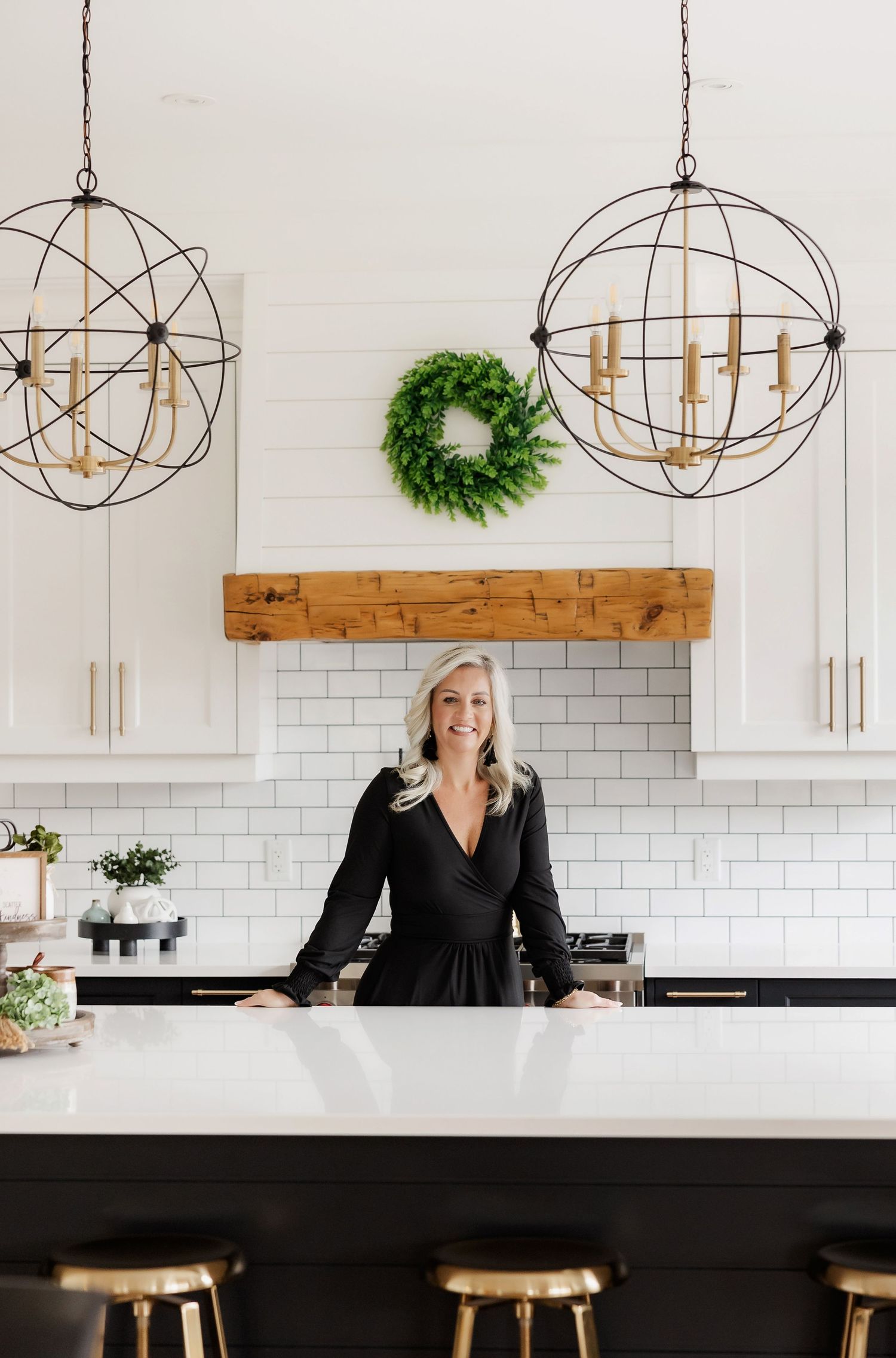 Bright kitchen featuring orb pendant lights, white cabinets and subway tile with wooden beam detail.