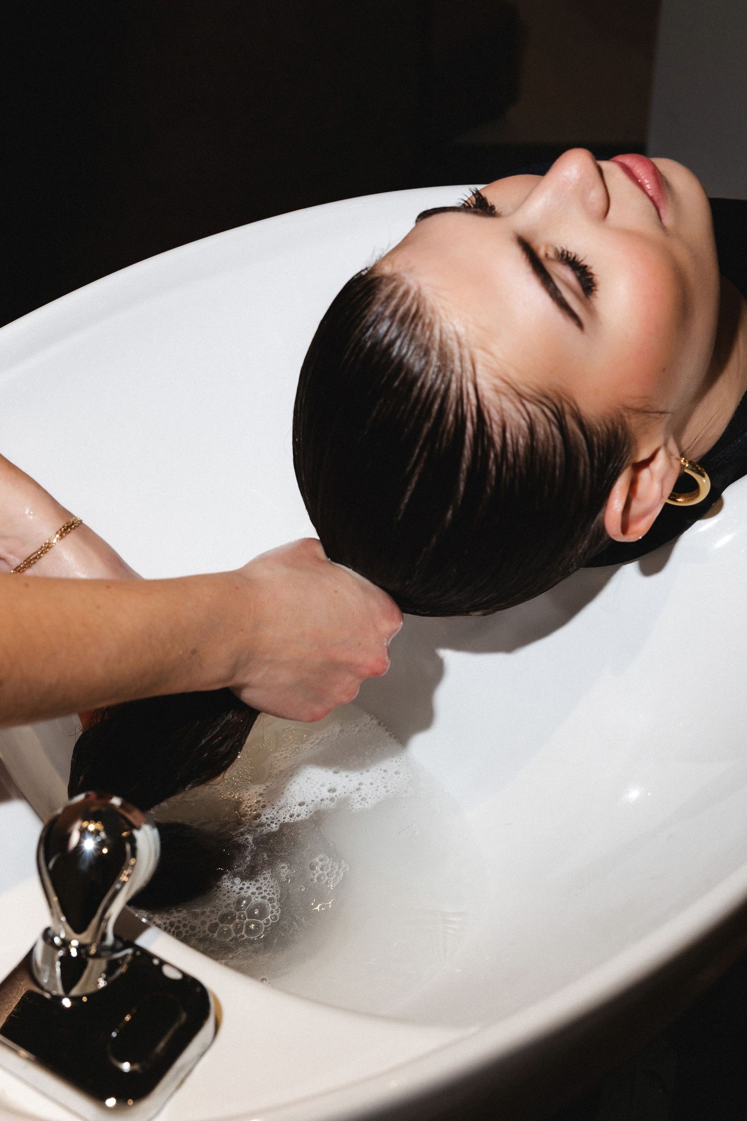 Professional hair washing service at modern salon sink.