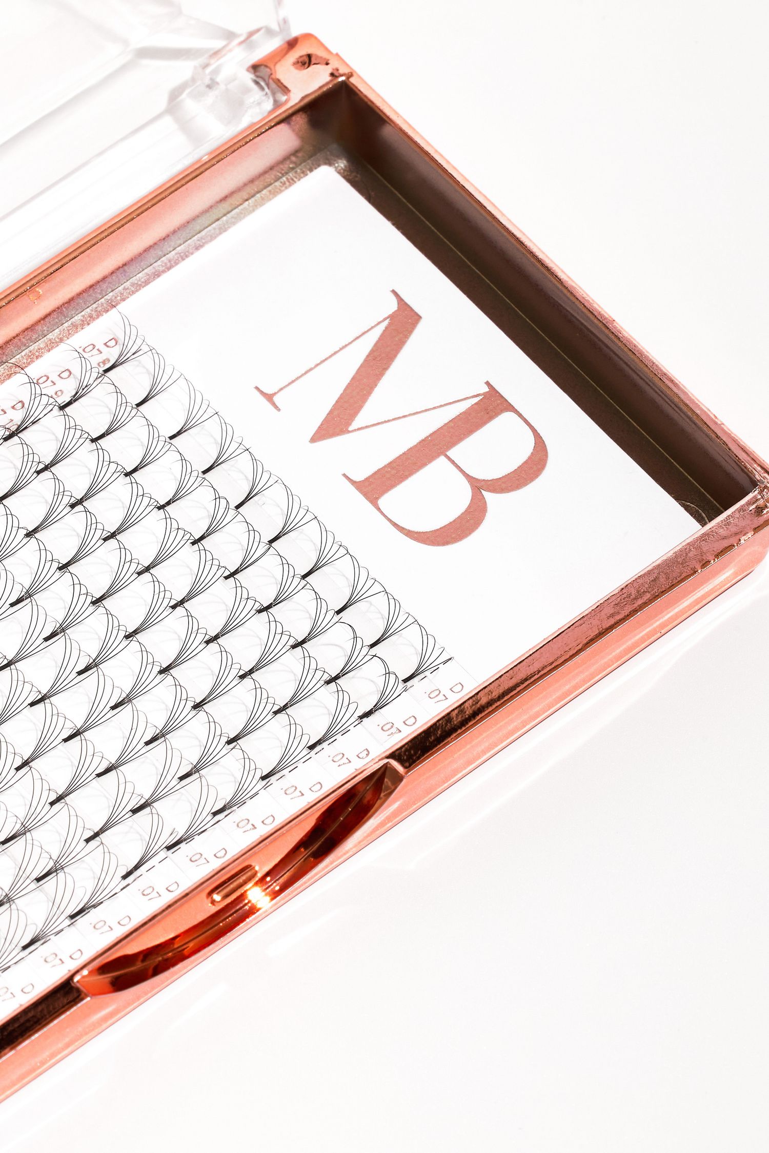 Rose gold beauty case containing organized false eyelash strips with MB branding.
