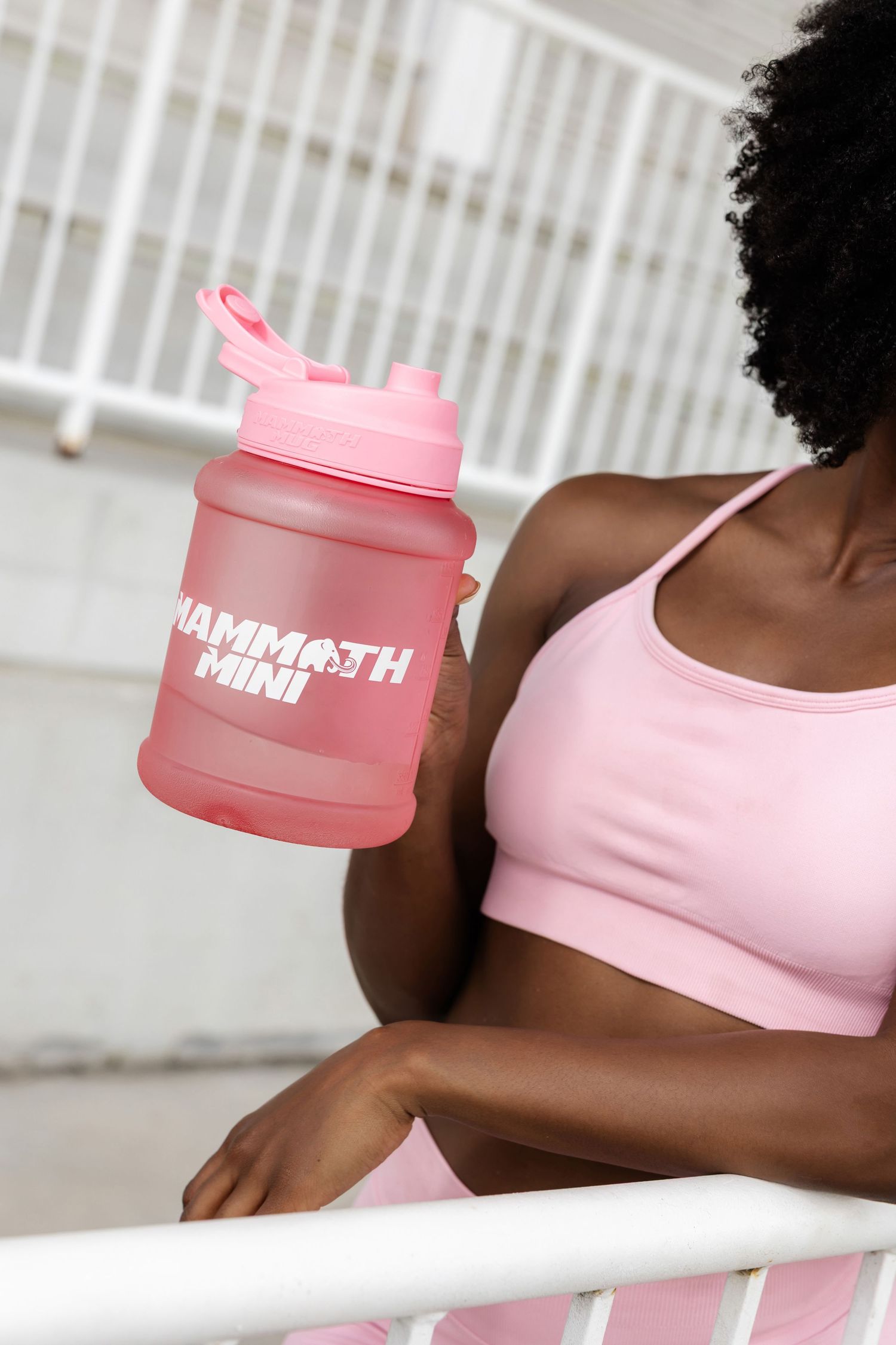 Close up of pink water bottle held by person in matching pink athletic wear.