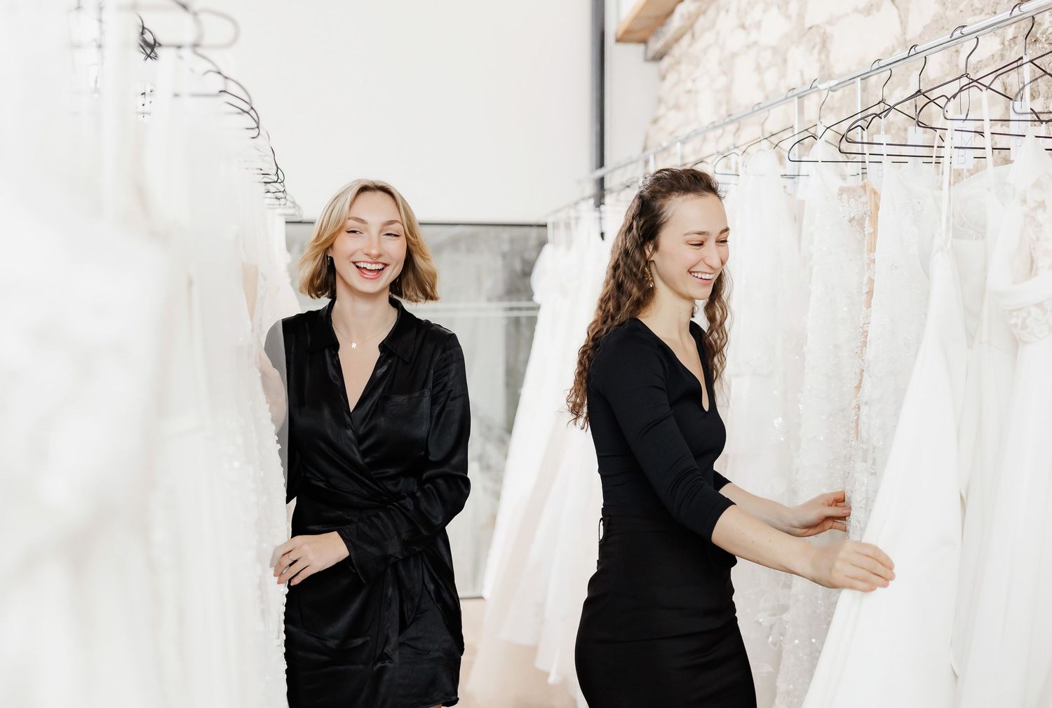 Staff members laughing and interacting between racks of wedding dresses.