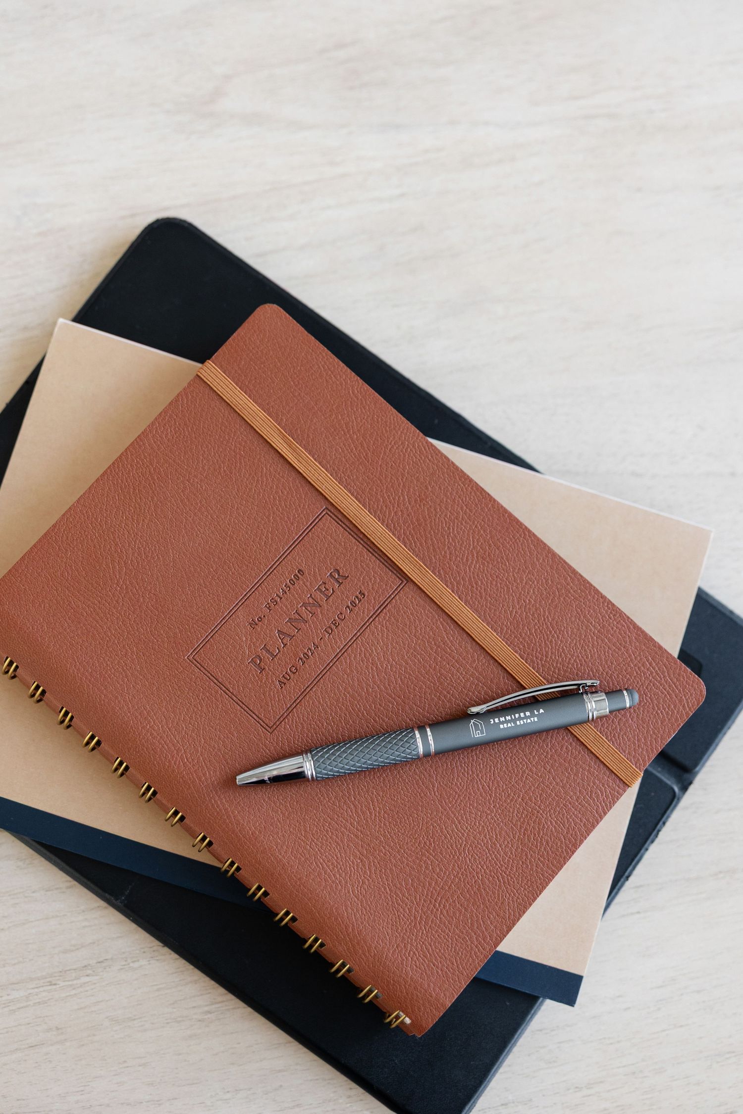 Brown leather notebook with pen on dark surface in minimal composition.