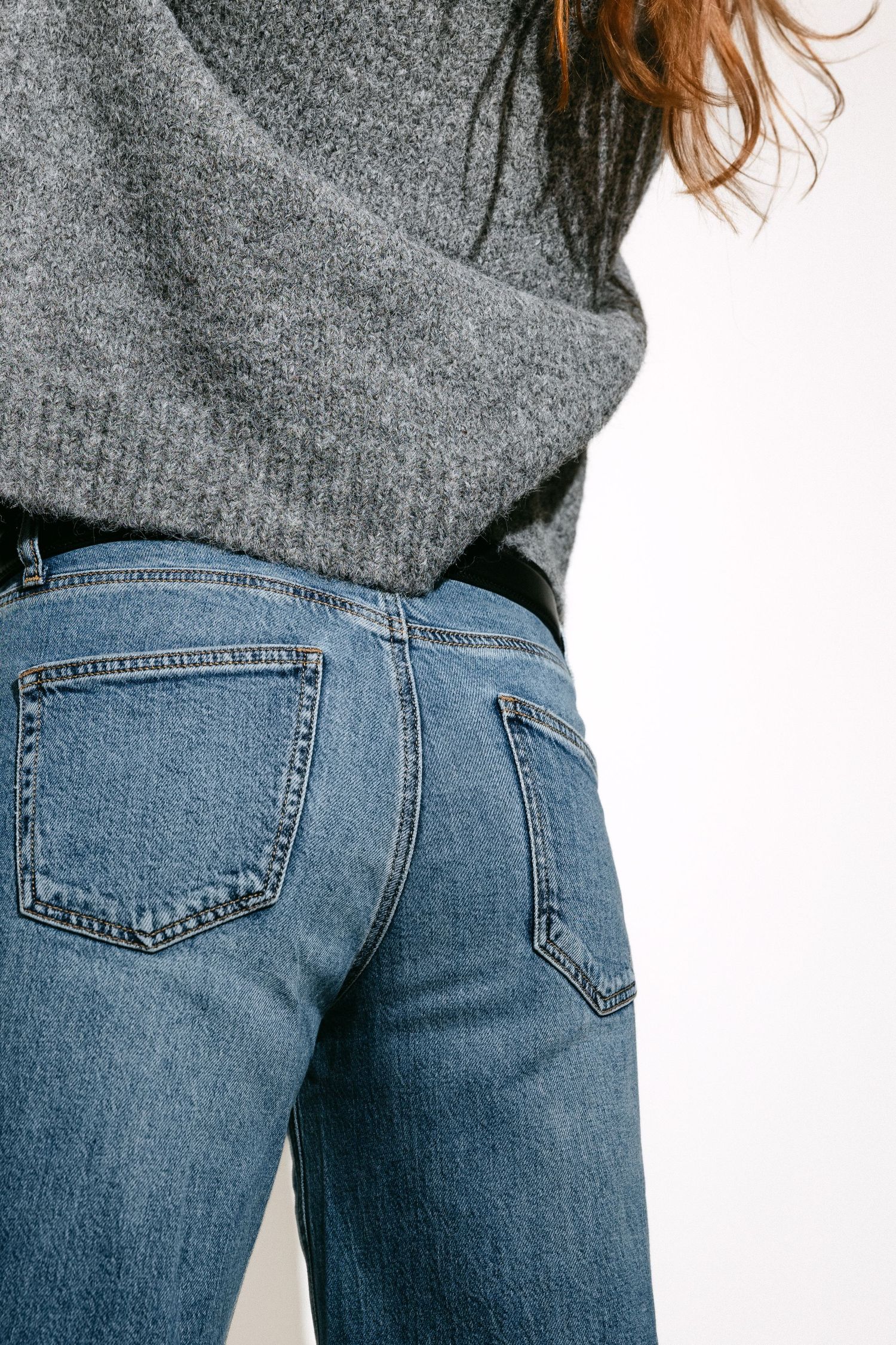 Back view of classic blue denim jeans paired with grey knit sweater.