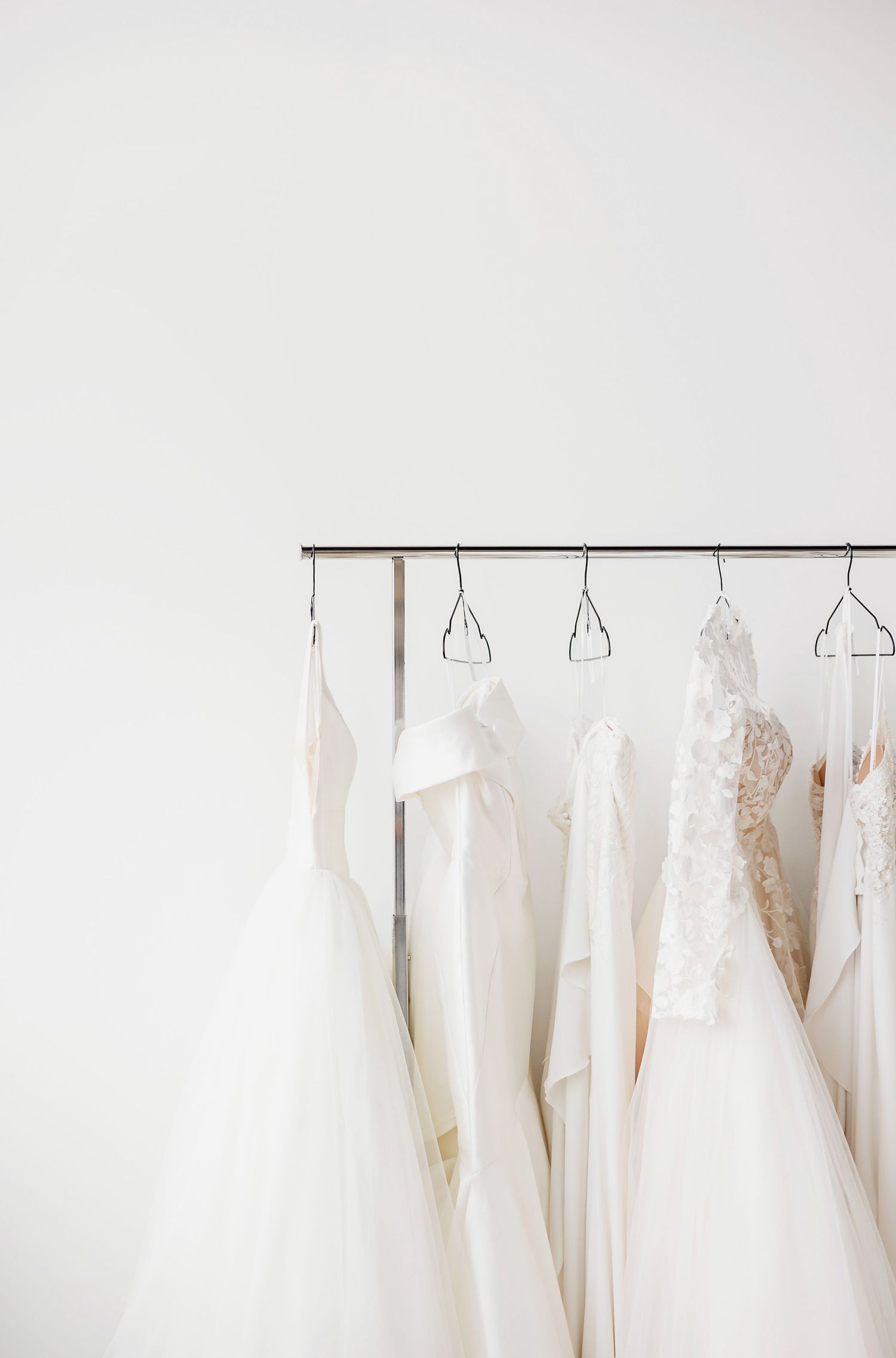 Collection of white and ivory wedding dresses hanging on a modern display rack.