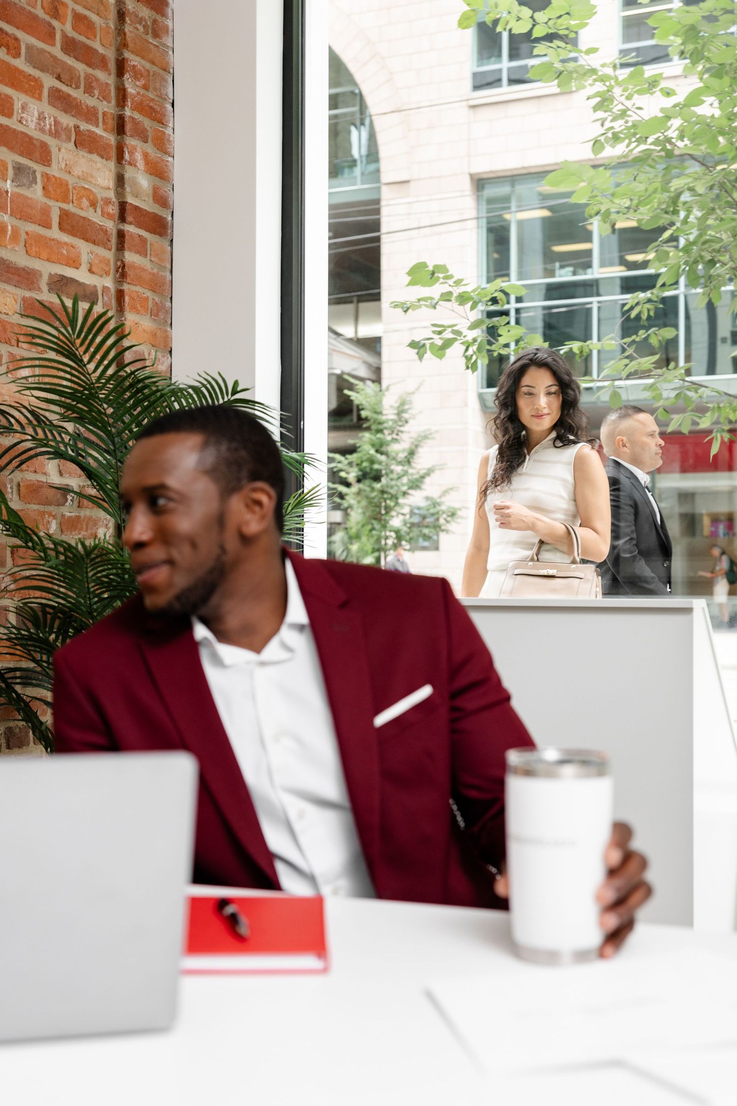 Professional meeting in bright office space with burgundy suit and laptop.