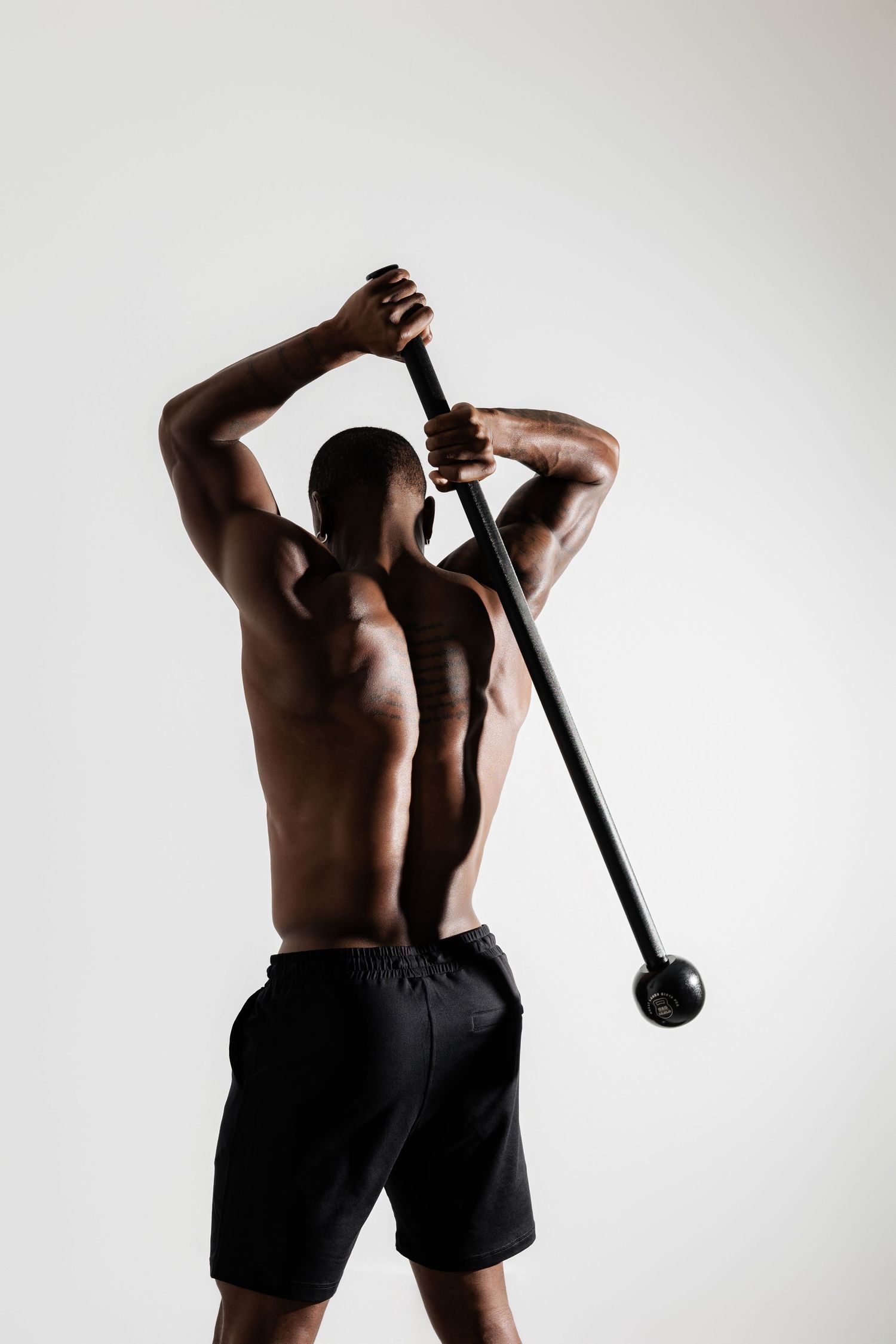 Athletic figure performing exercise with steel bar against white background.