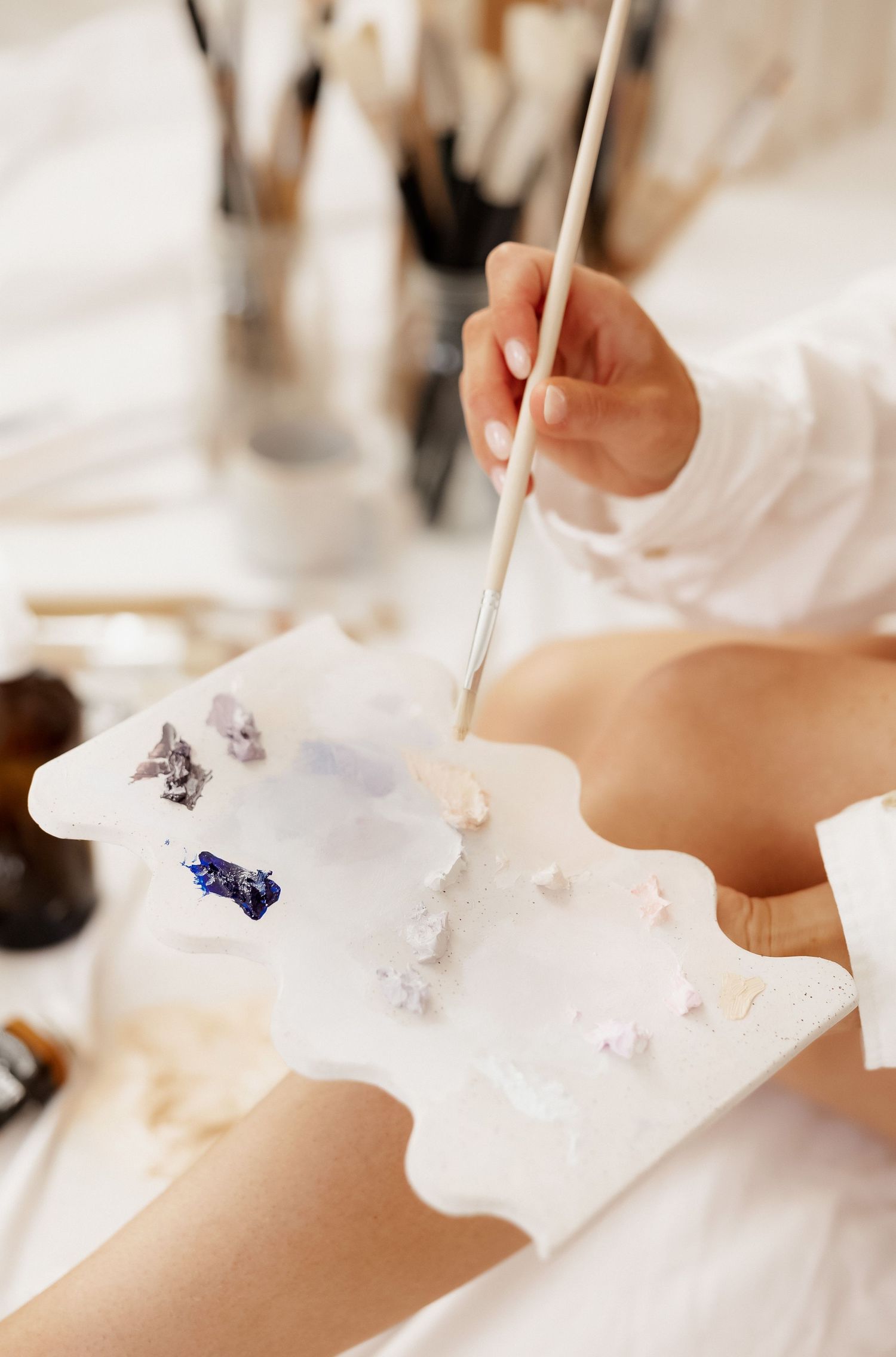 Close-up of paint mixing on white palette with various colors.