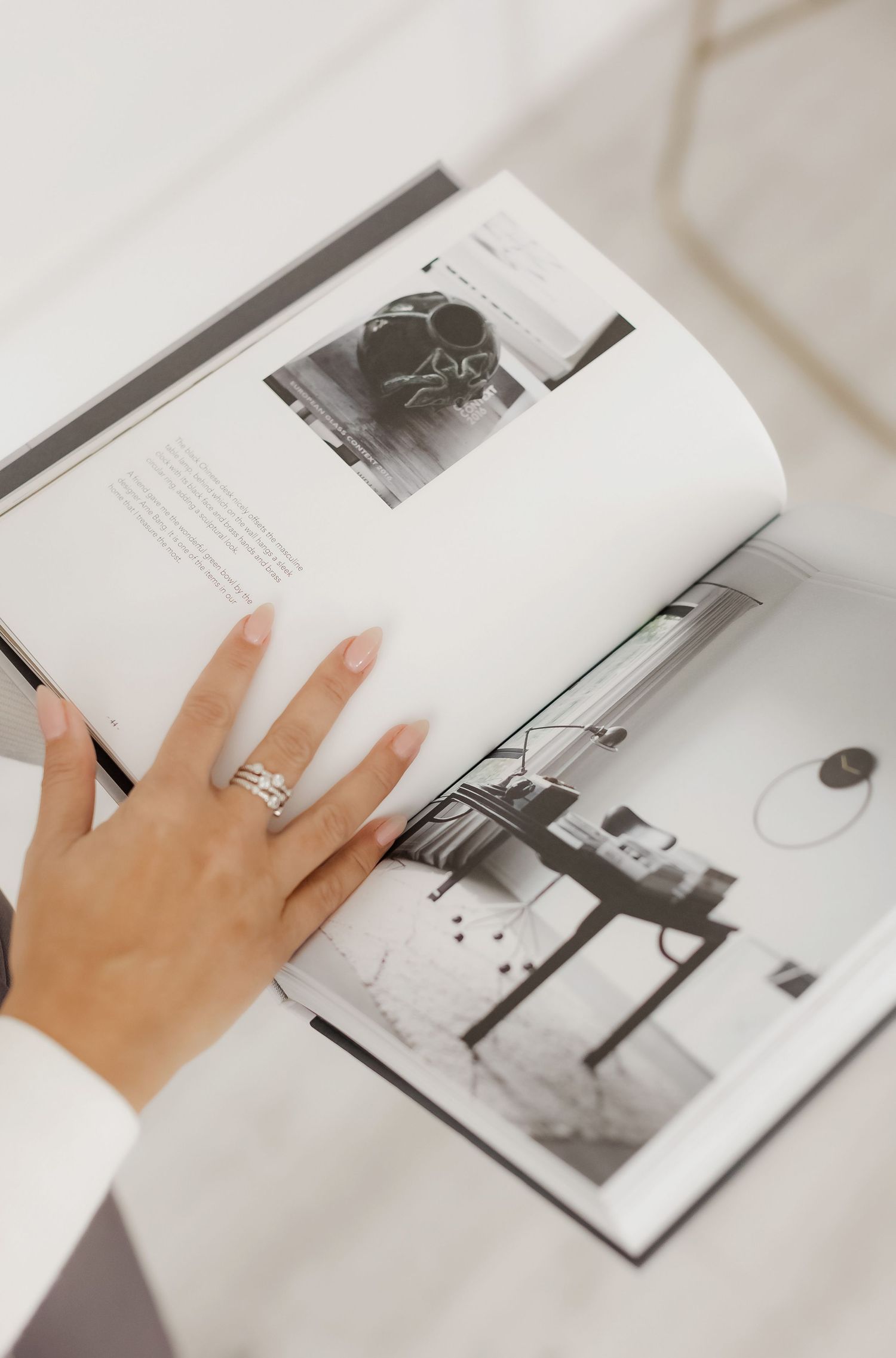 Close-up of hands turning pages in a black and white interior design book on white surface.