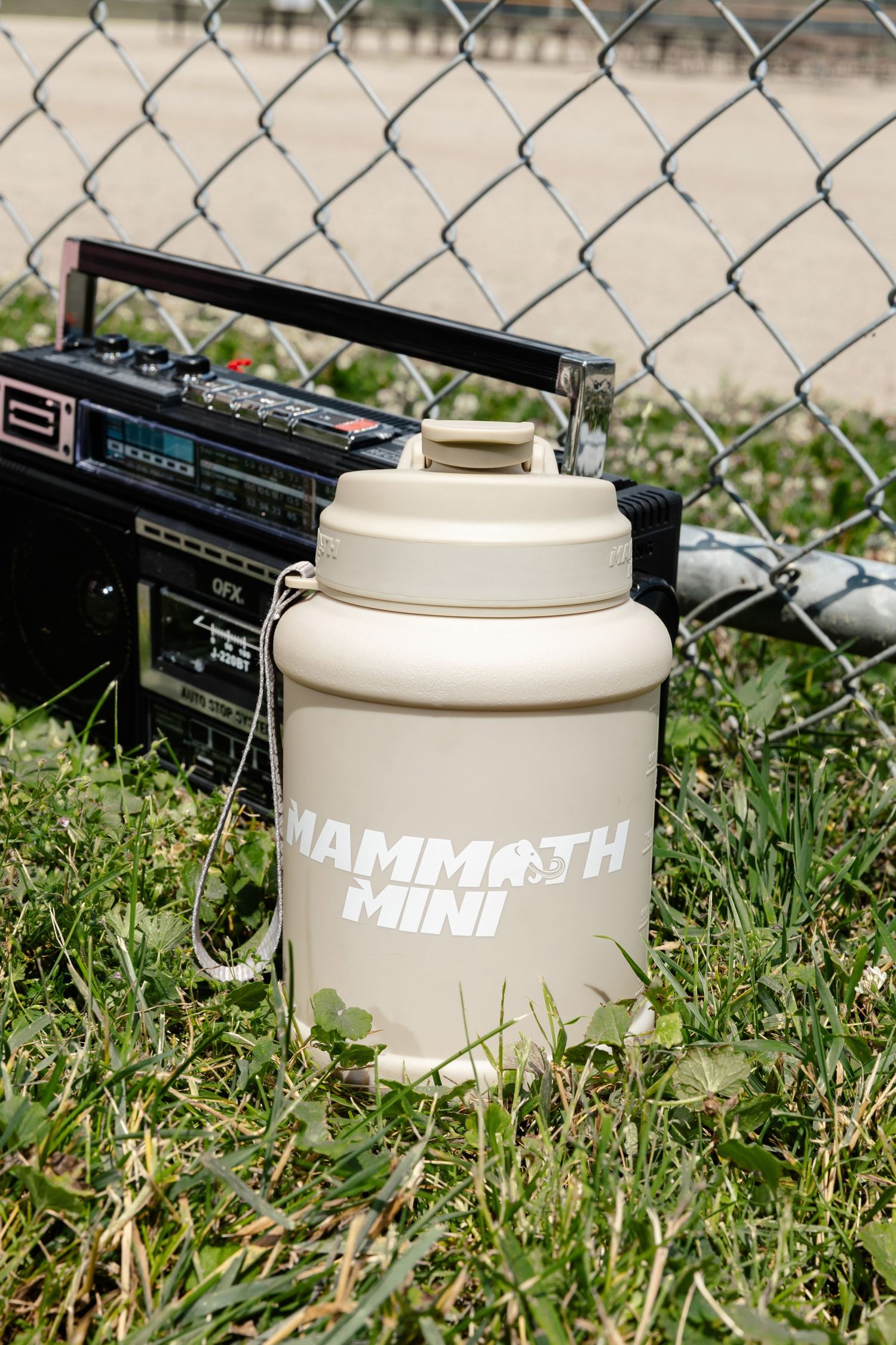 White protein shaker bottles arranged on grass next to chain link fence and boombox.