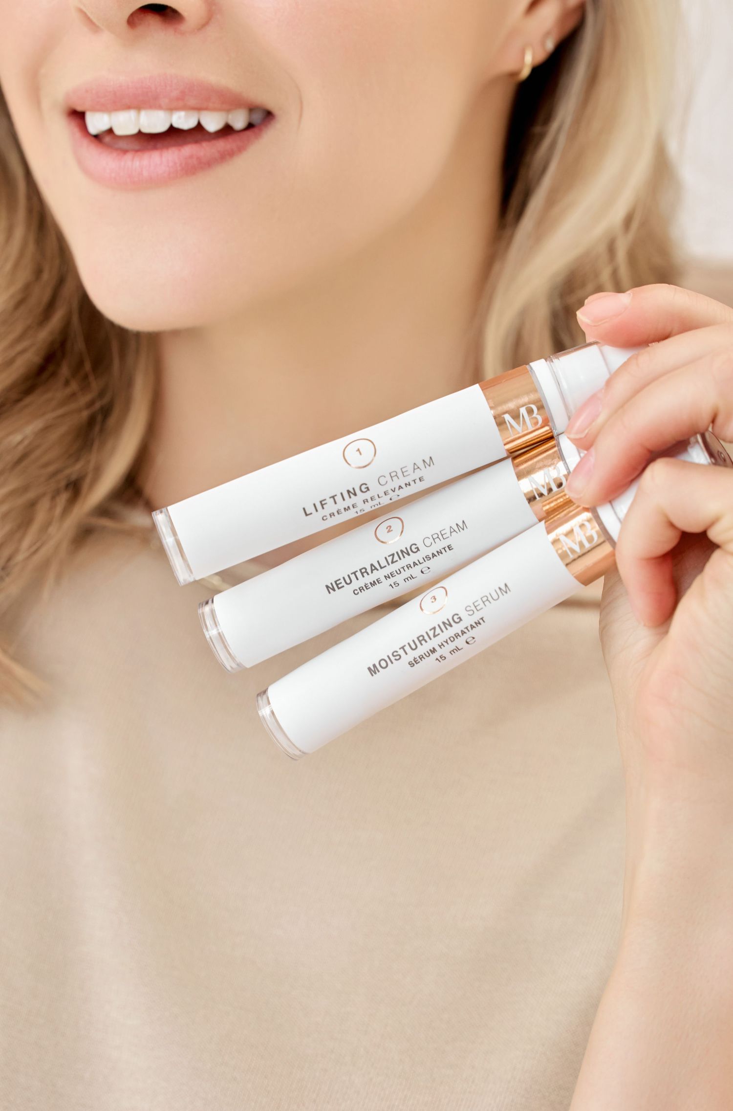 Display of white cosmetic product tubes being held against beige background.