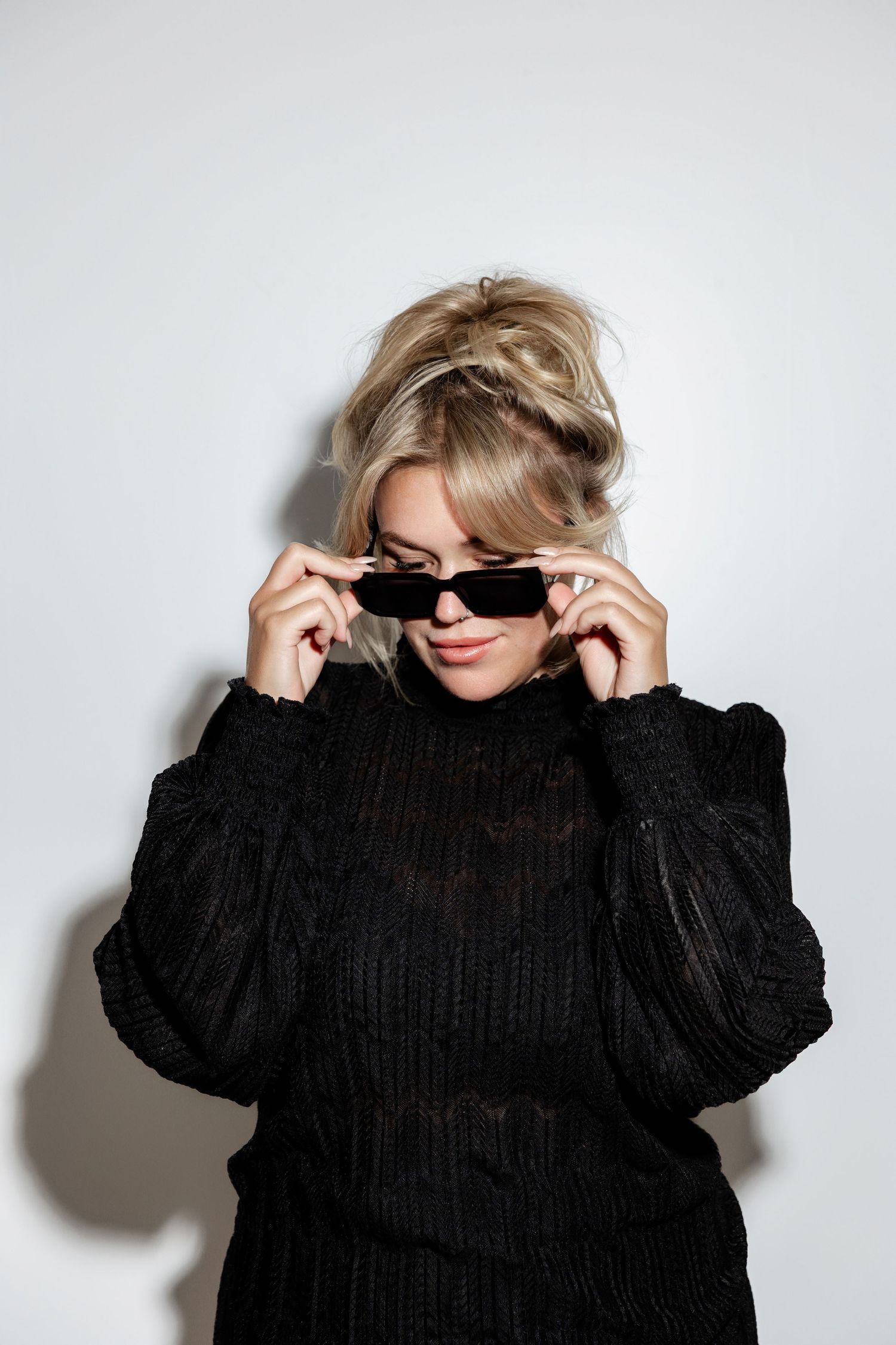 Fashion series showing black sweater and sunglasses styling against white background.