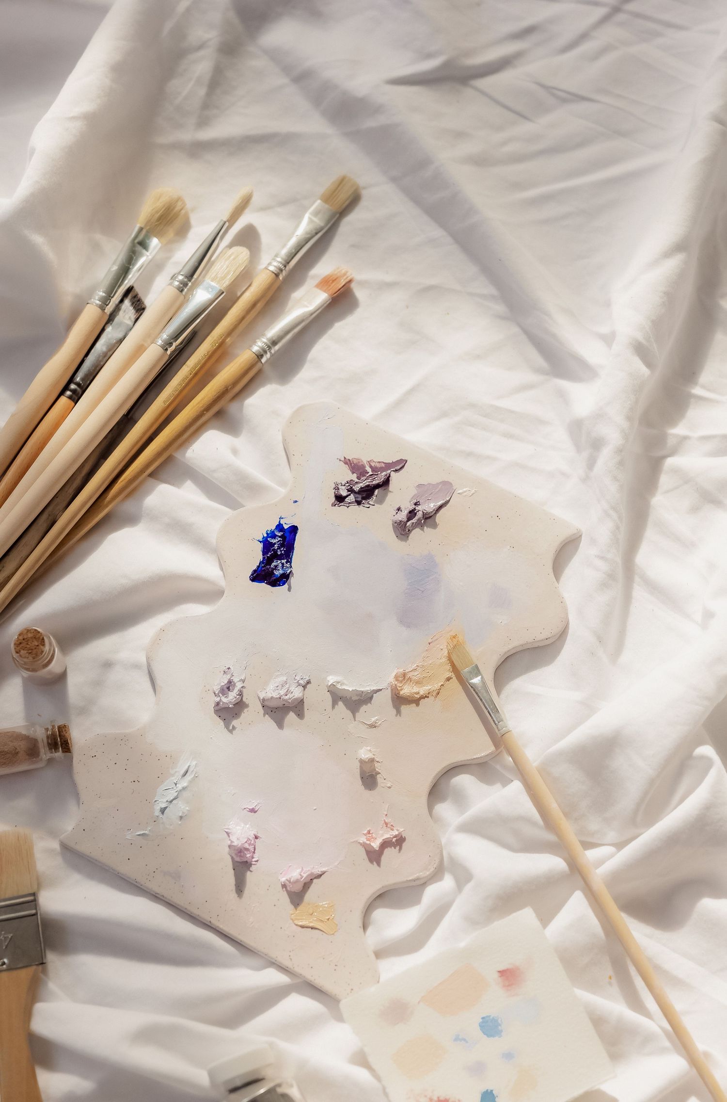Art supplies and decorative butterflies arranged on white fabric background.