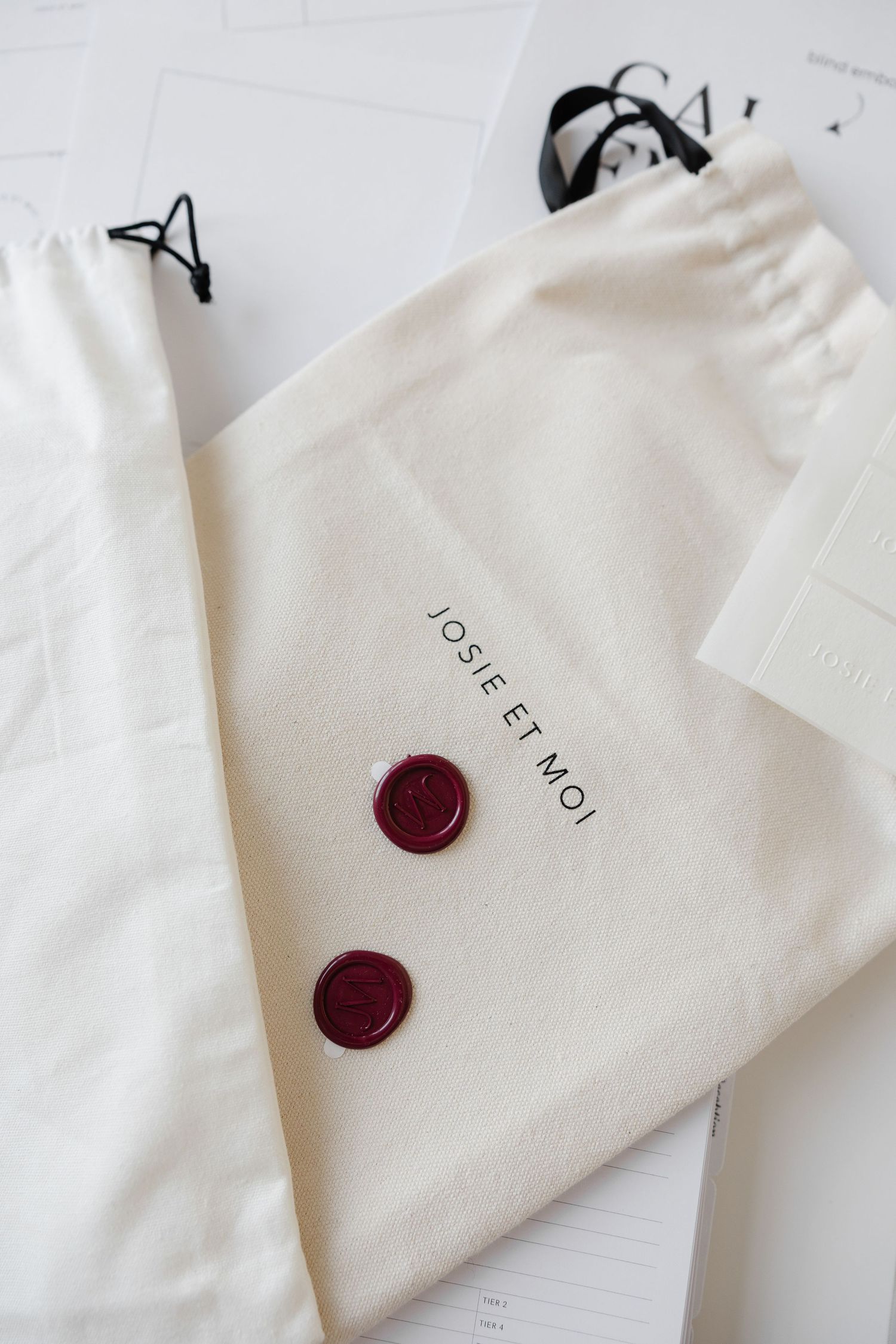 Clean white fabric bags with red wax seals and branding displayed on light surface.