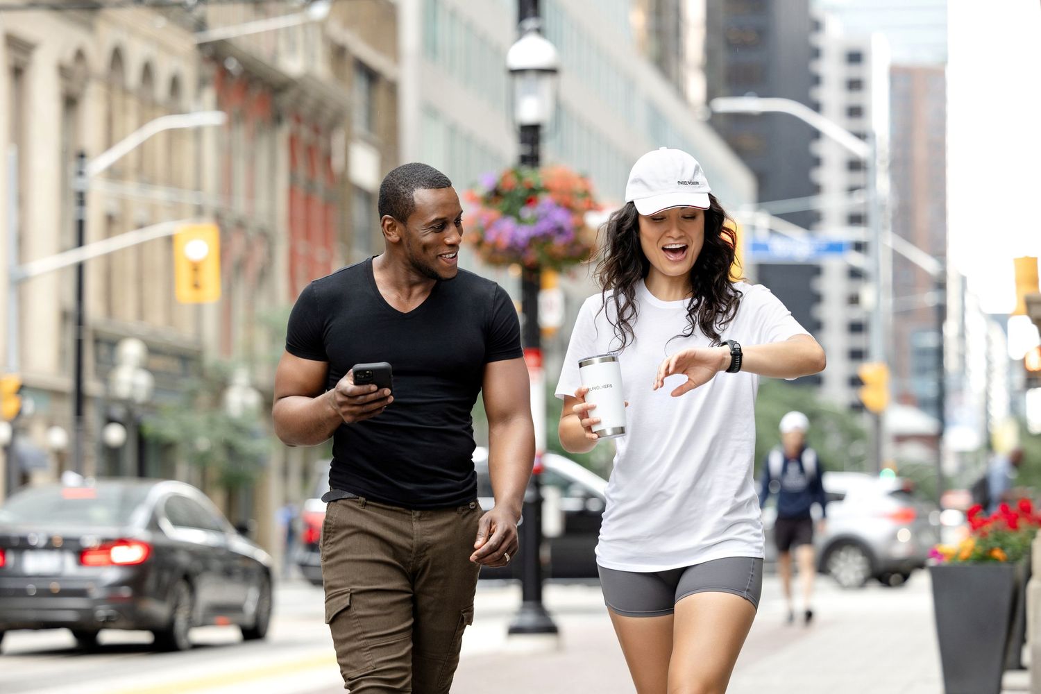 Two people jogging together on a city street with tall buildings in the background.