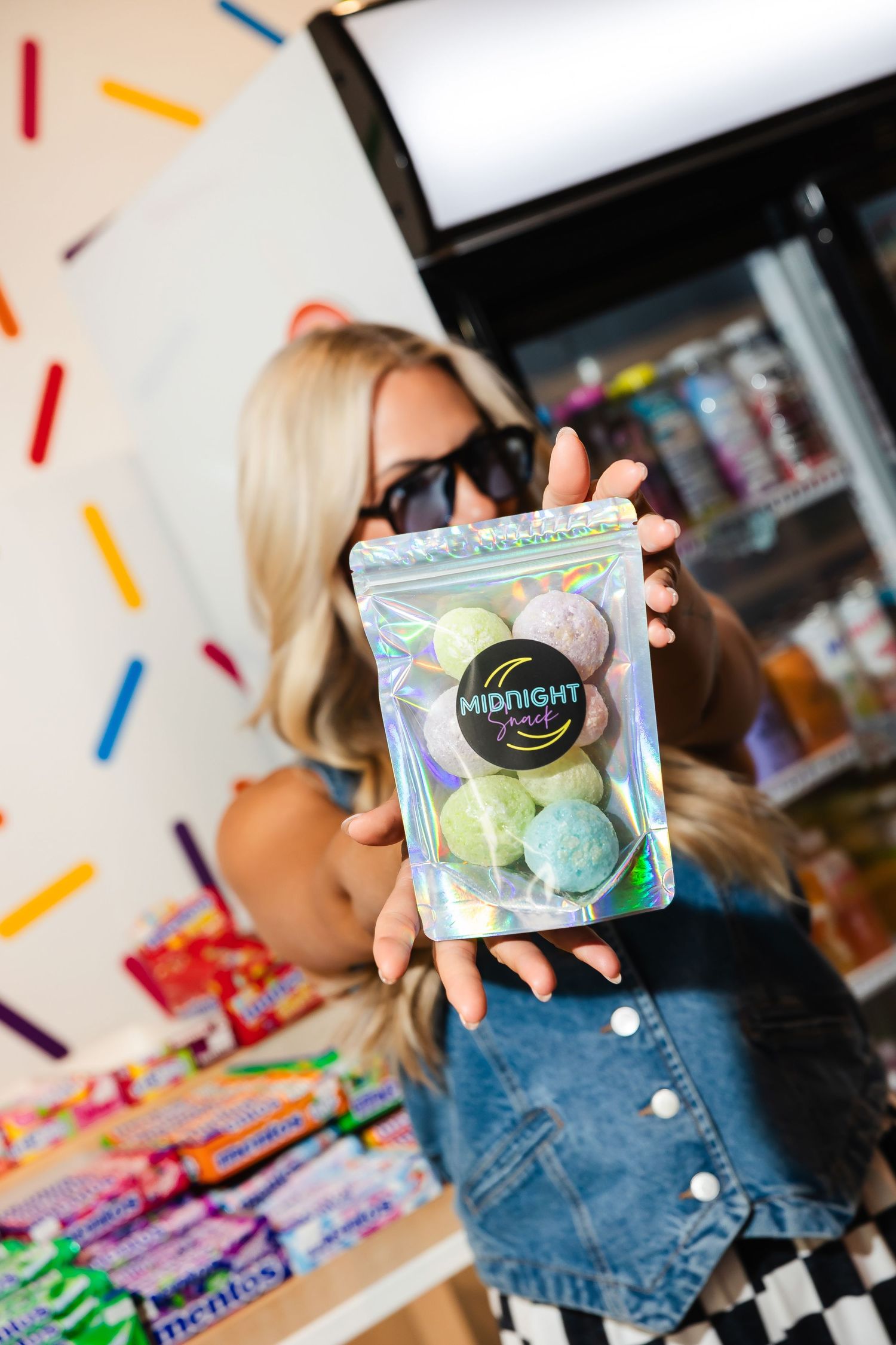 Displaying colorful candy packages with the Midnight brand logo against a festive sprinkle background.